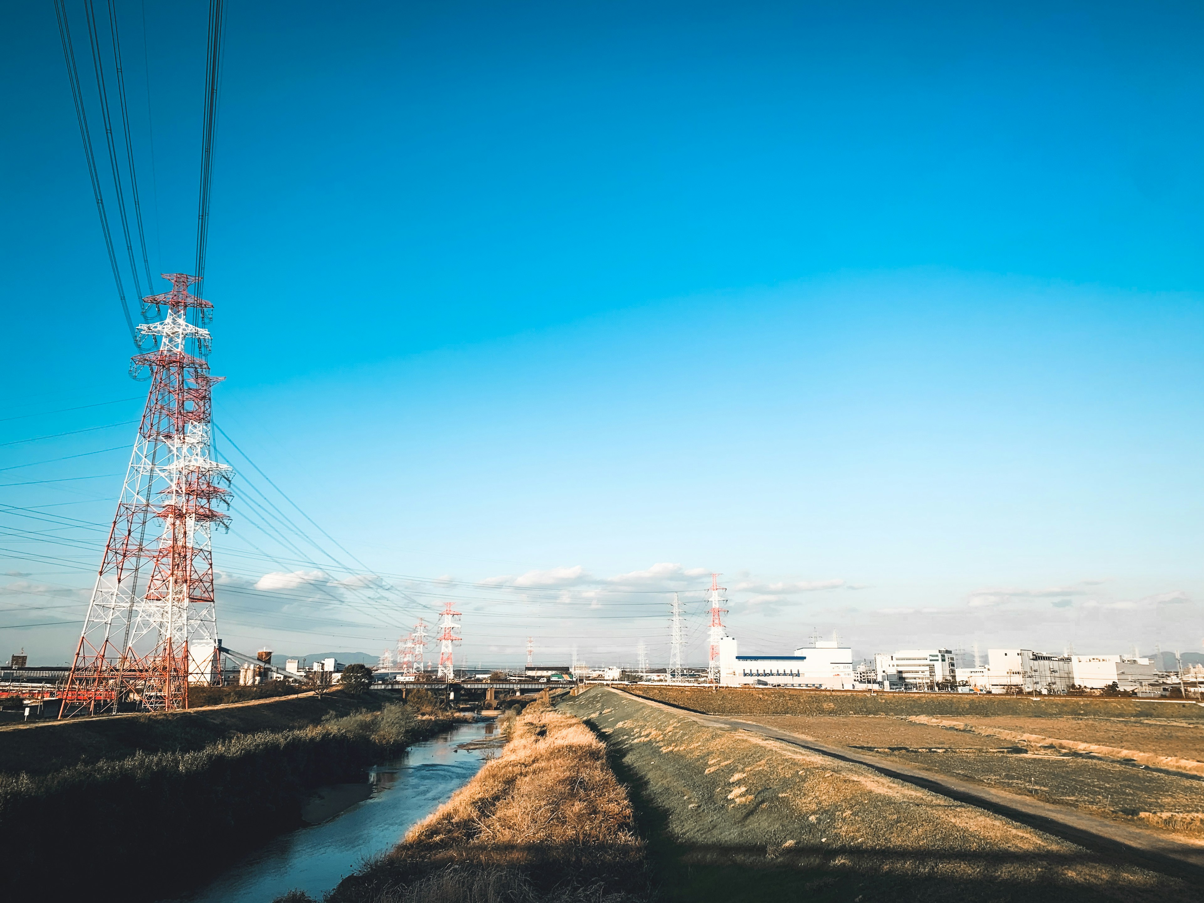 Ländliche Landschaft mit Stromleitungen unter einem klaren blauen Himmel