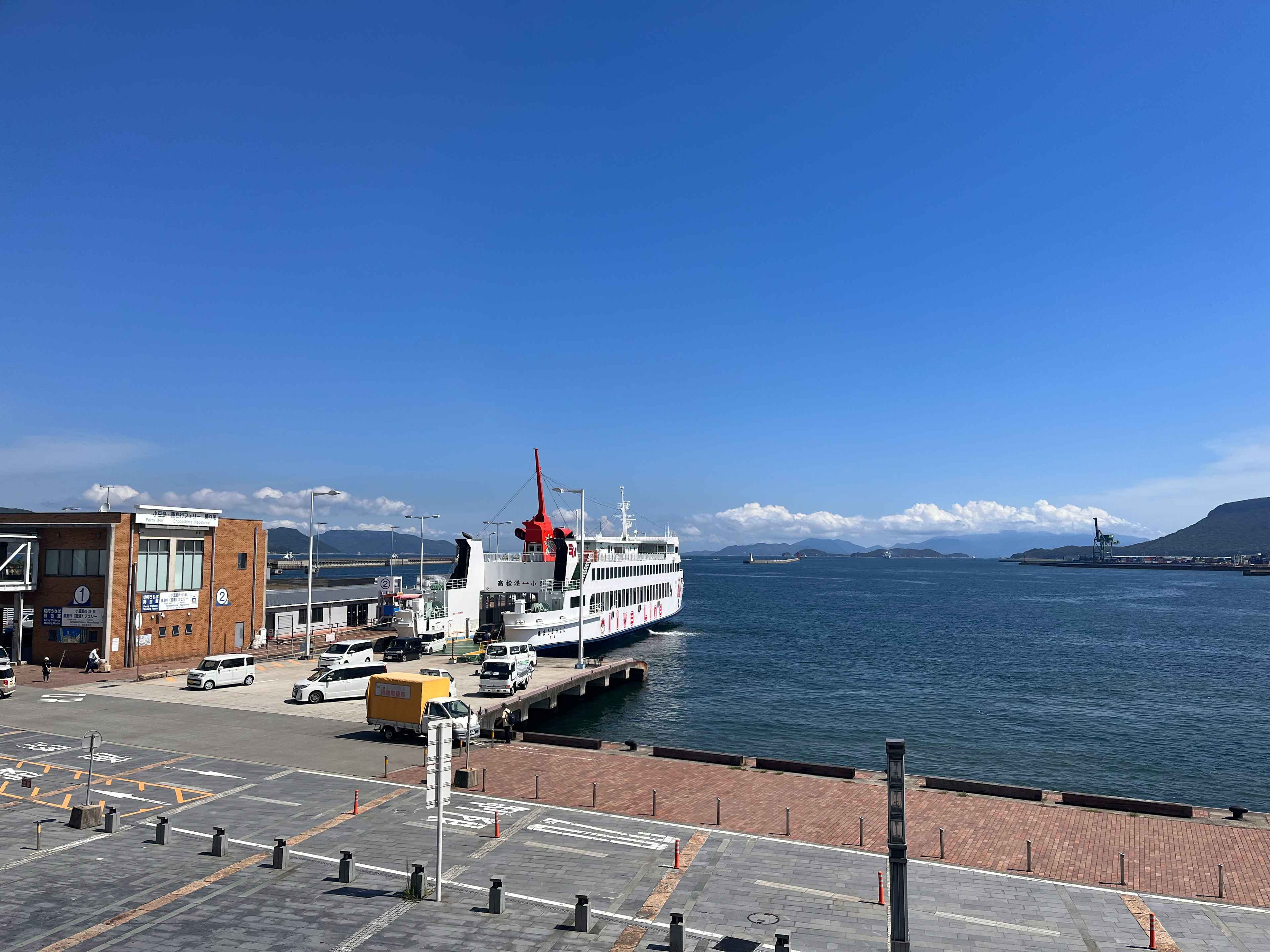 Harbor scene with a white ferry and red flag under a clear blue sky