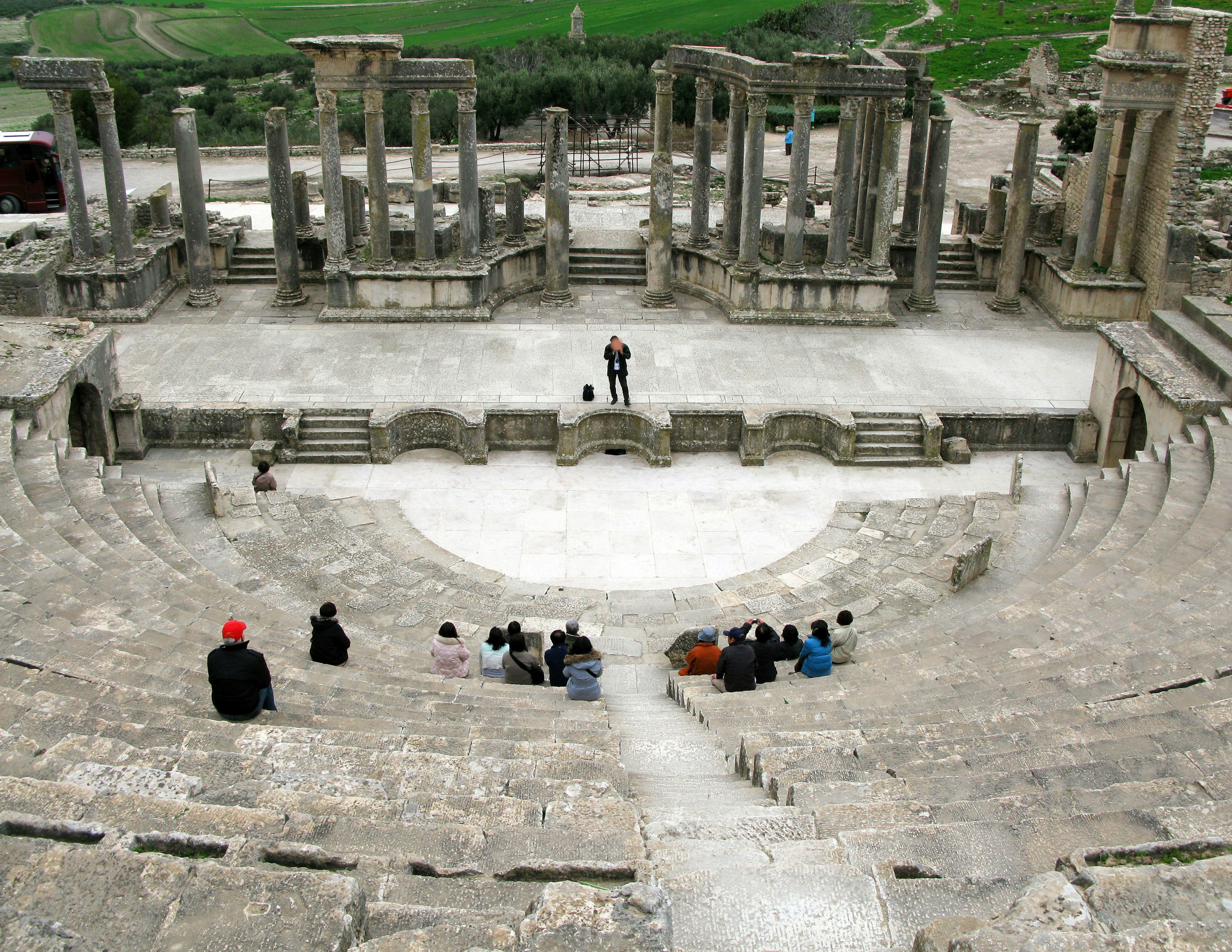 Ruines d'un théâtre ancien avec un orateur et des membres du public