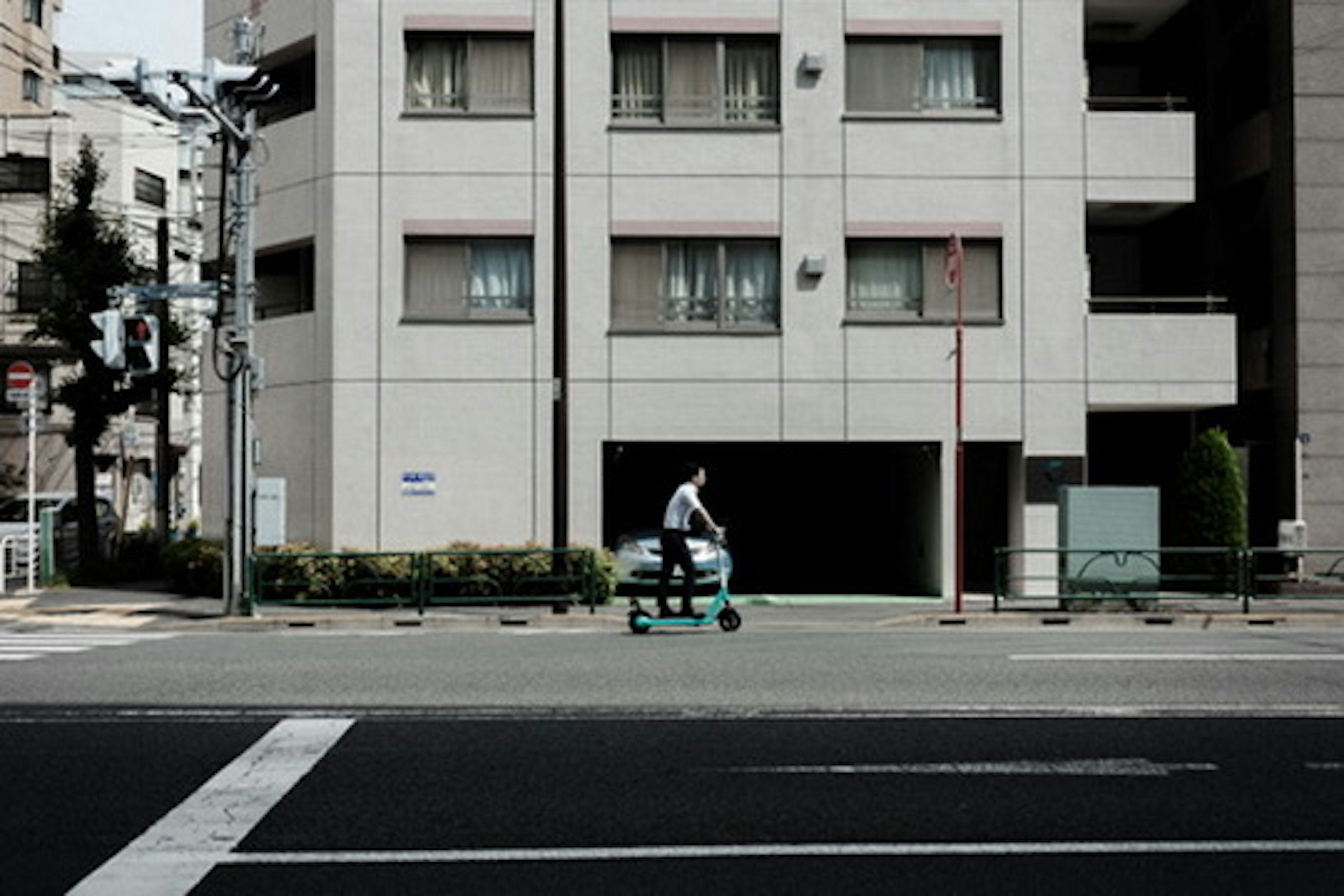 Persona montando un scooter frente a un edificio blanco