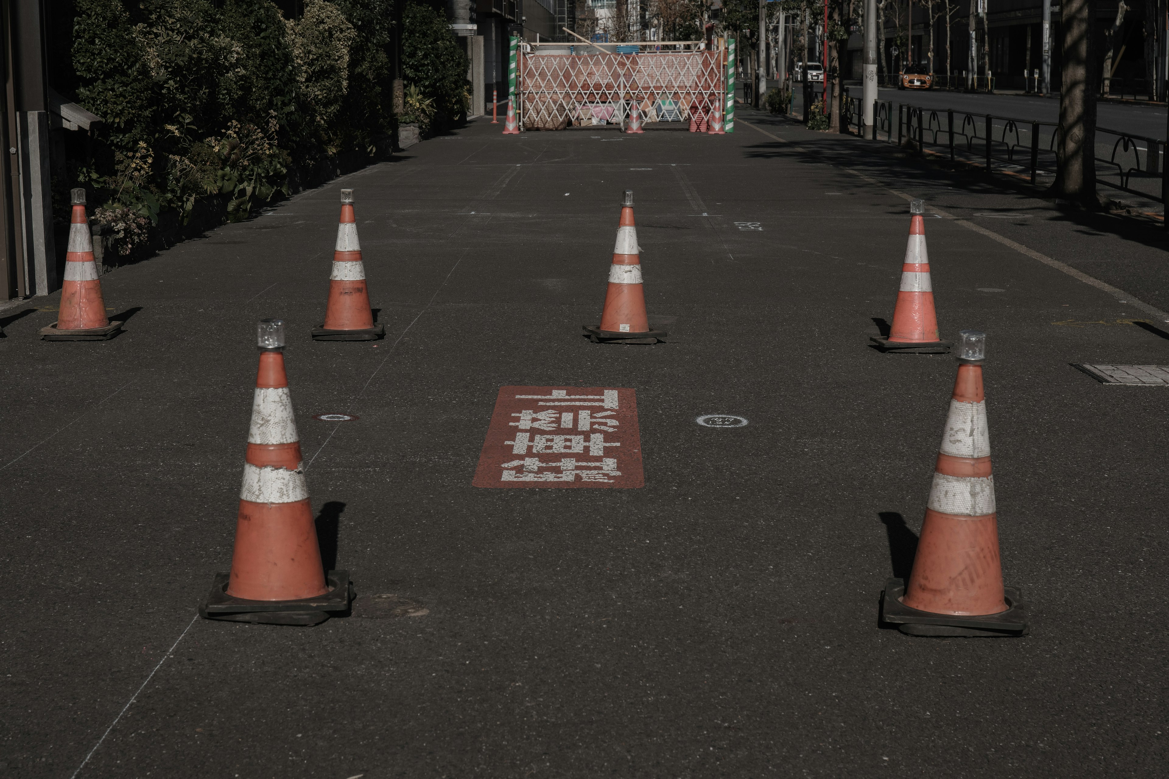 Scene with orange traffic cones arranged on the road and a barrier in the background