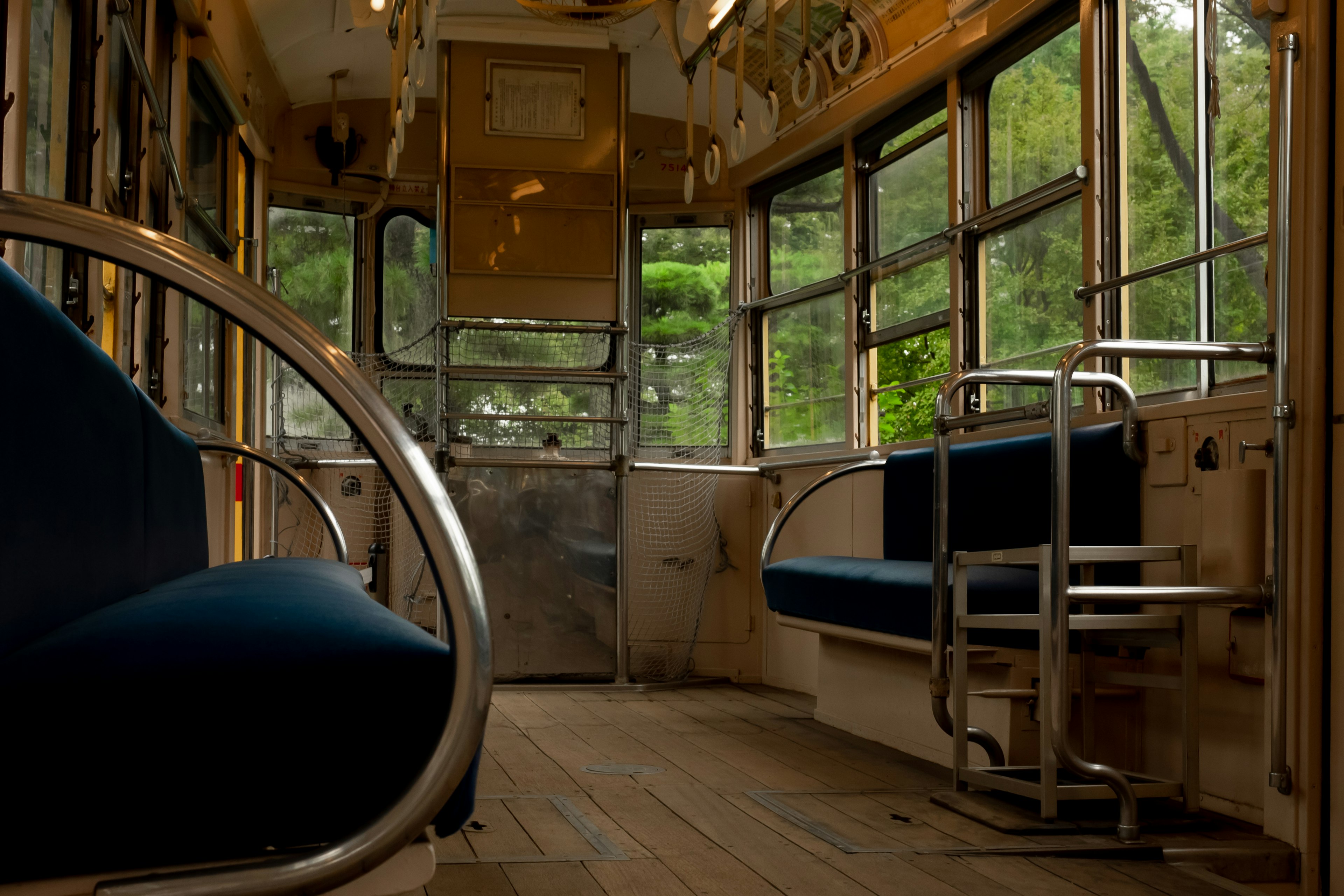 Interno di un vecchio autobus con sedili blu e pavimento in legno