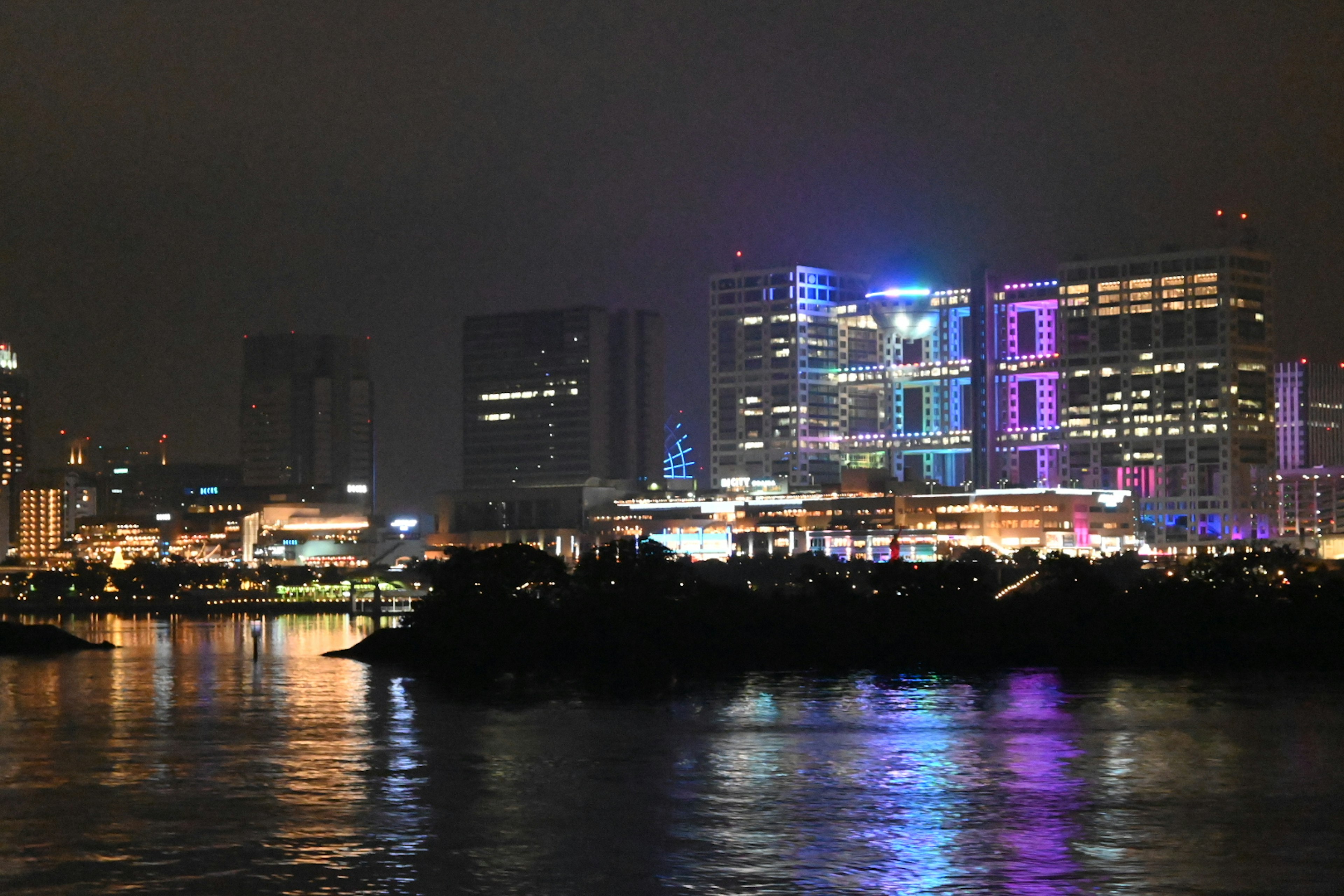 Skyline notturno con edifici luminosi che si riflettono sull'acqua