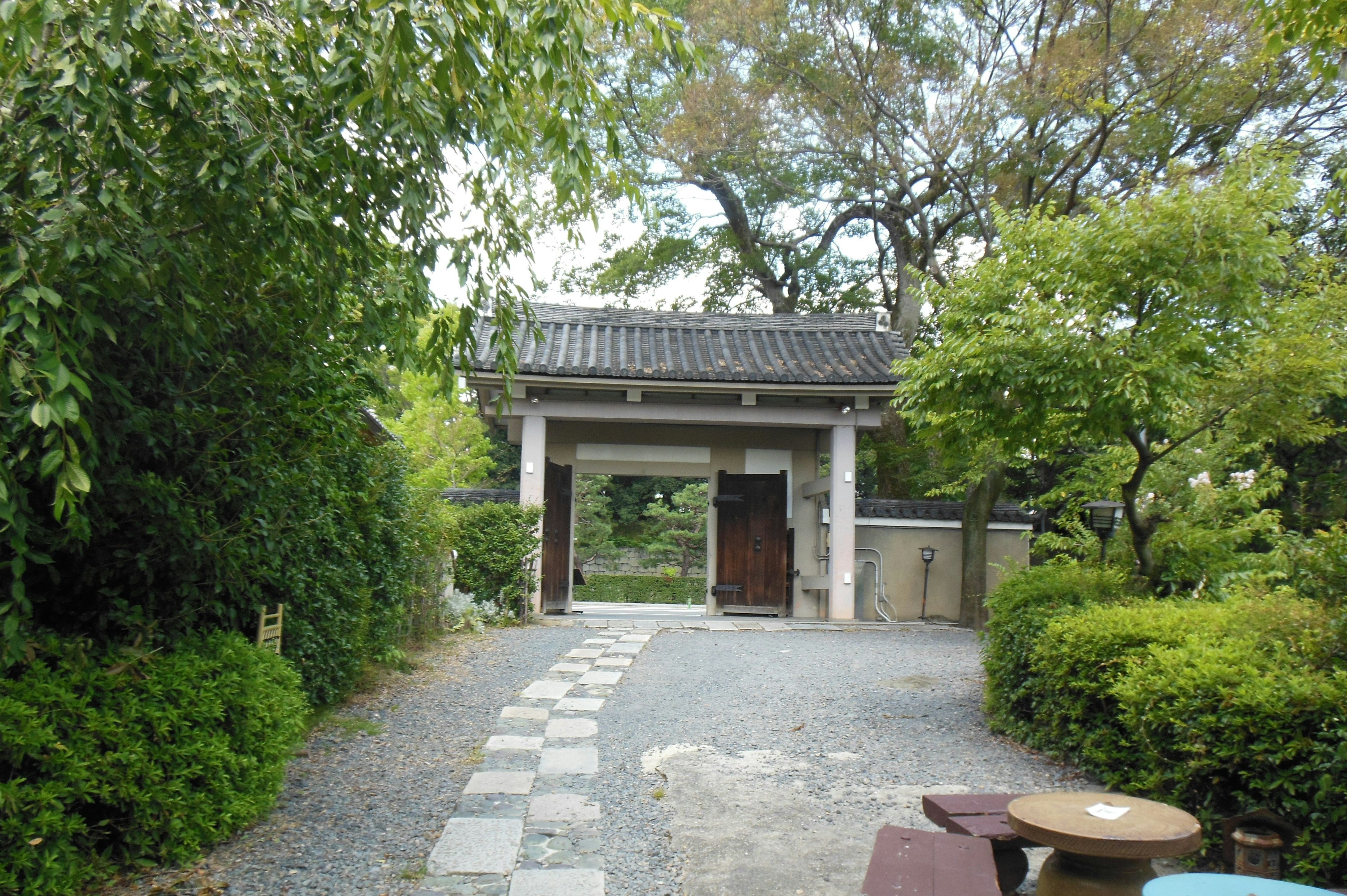 Traditional Japanese gate surrounded by stone pathway and lush greenery