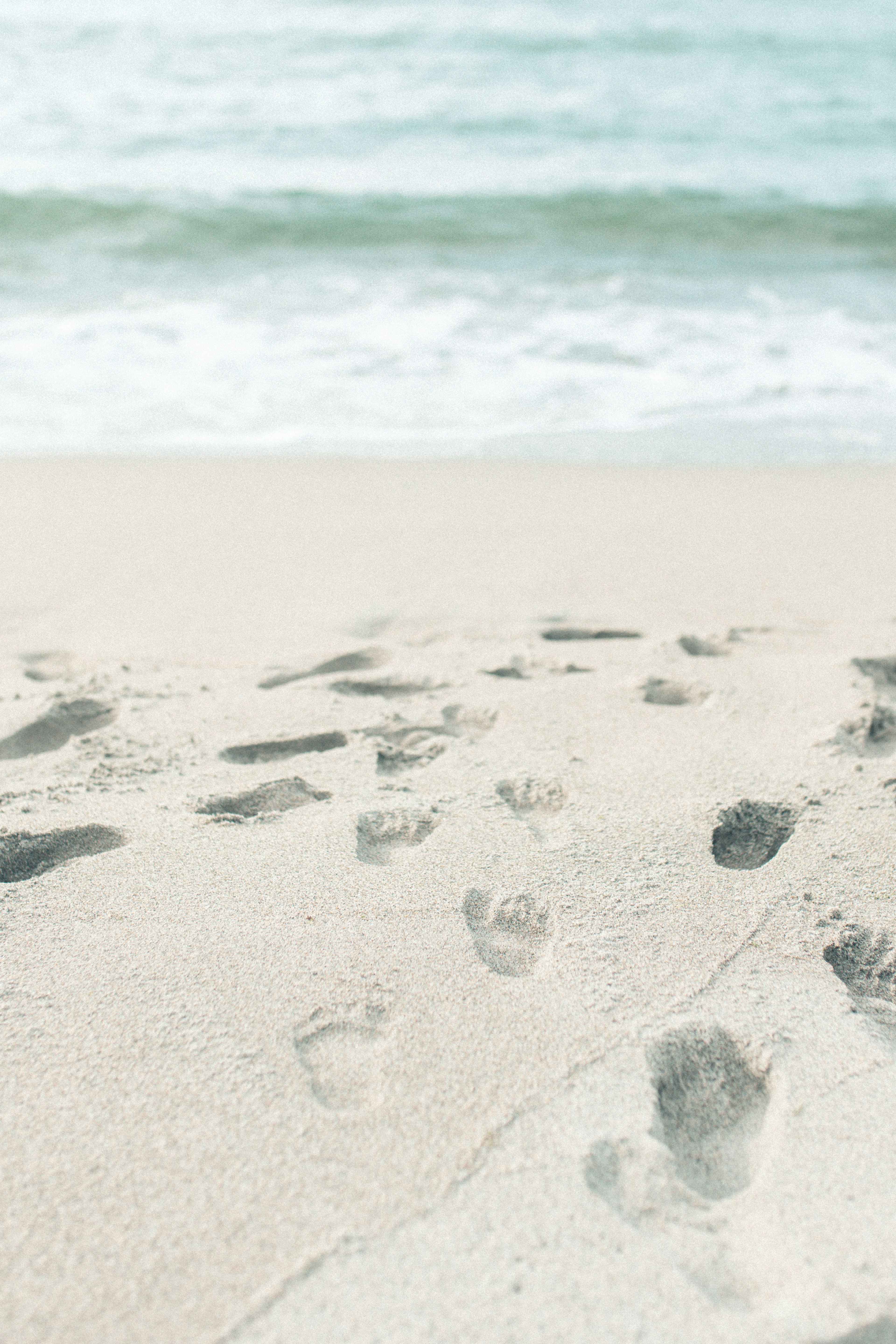 Footprints on a sandy beach with gentle waves in the background