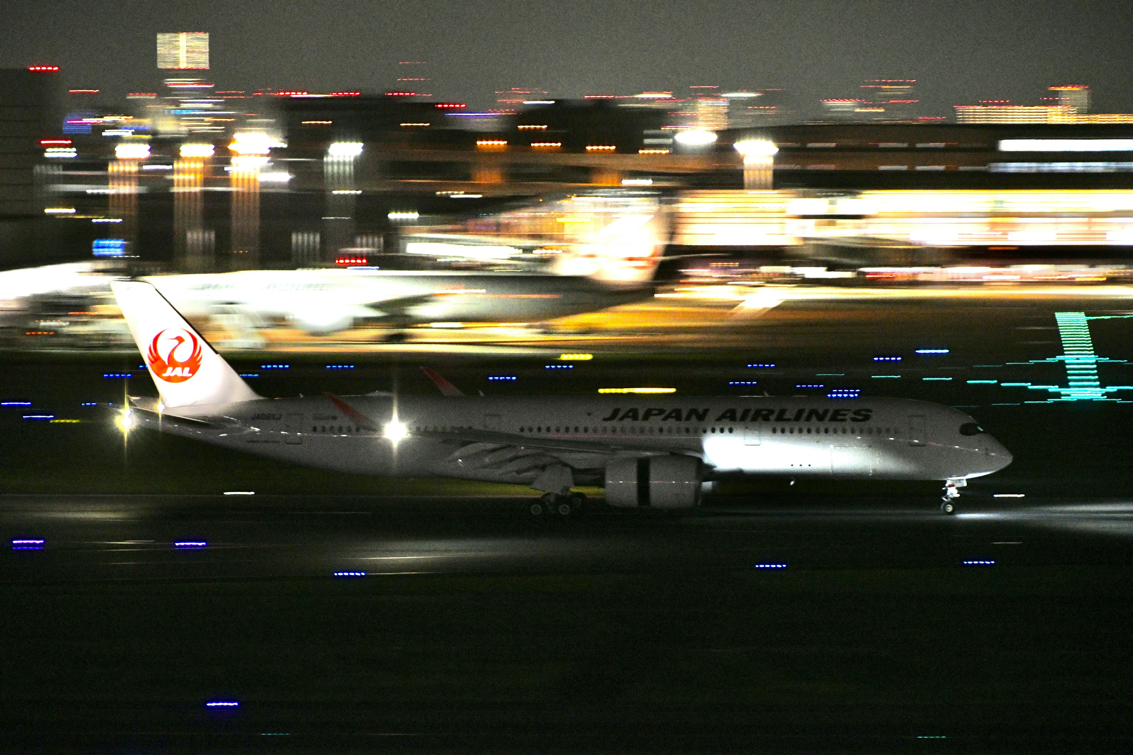 Japan Airlines passenger plane taxiing on runway at night