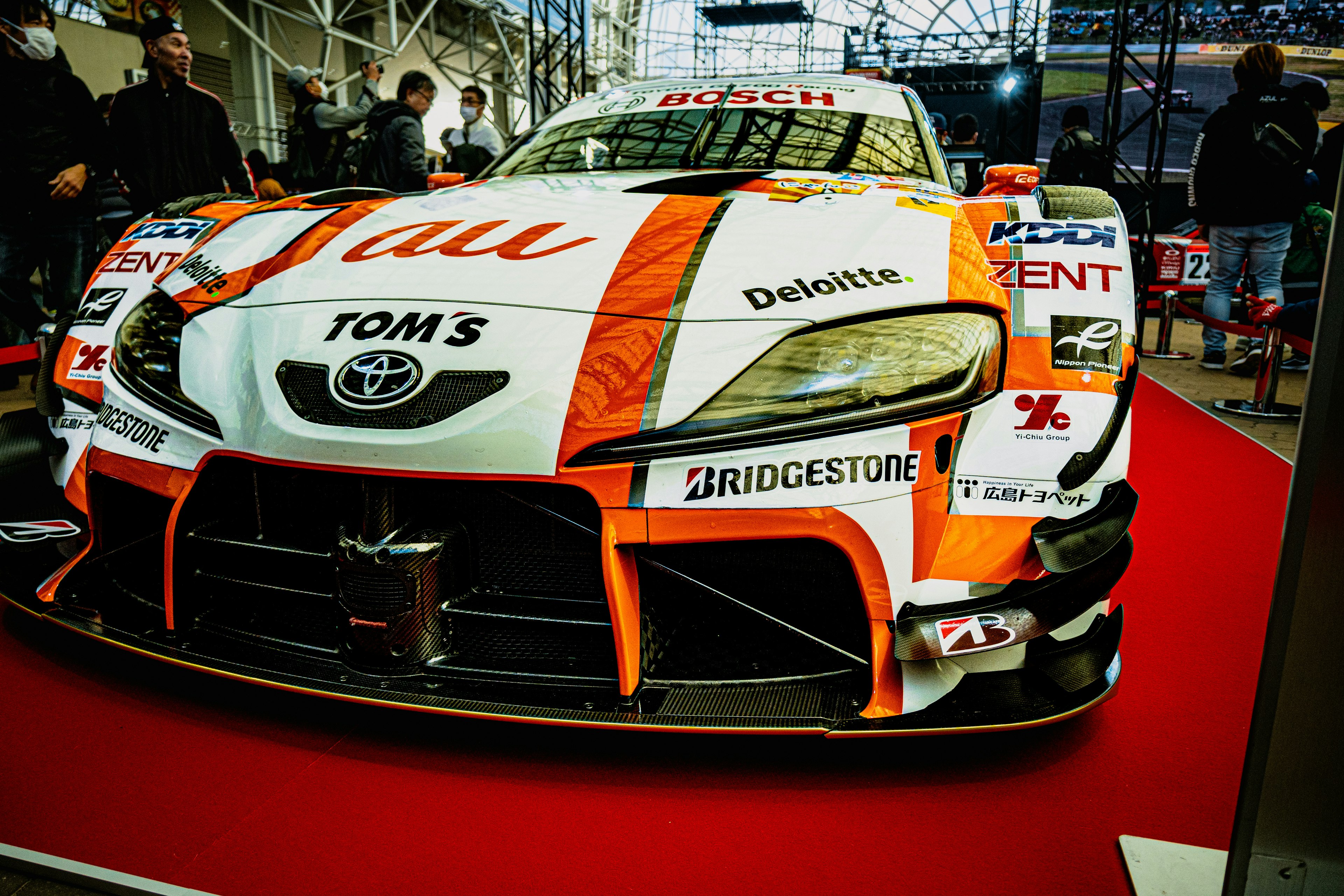 Coche de carreras Toyota exhibido en una alfombra roja con logotipos de patrocinadores