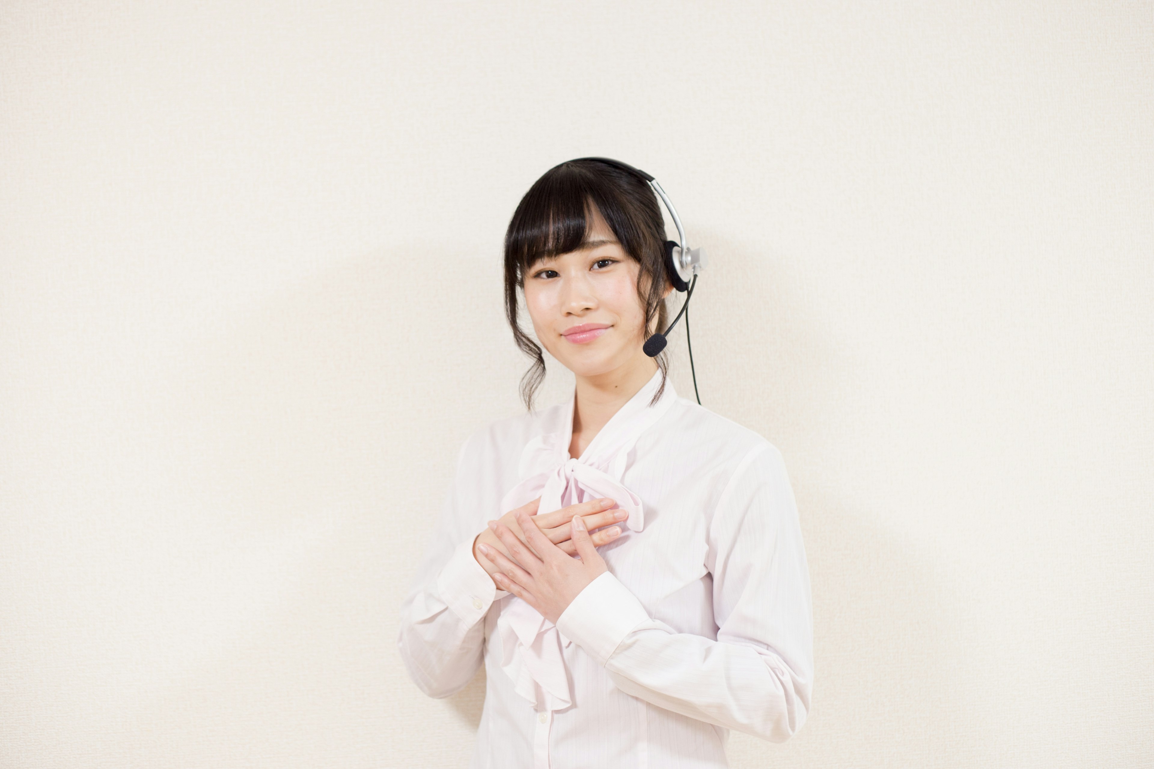 A woman in a white uniform smiling with her hands on her chest