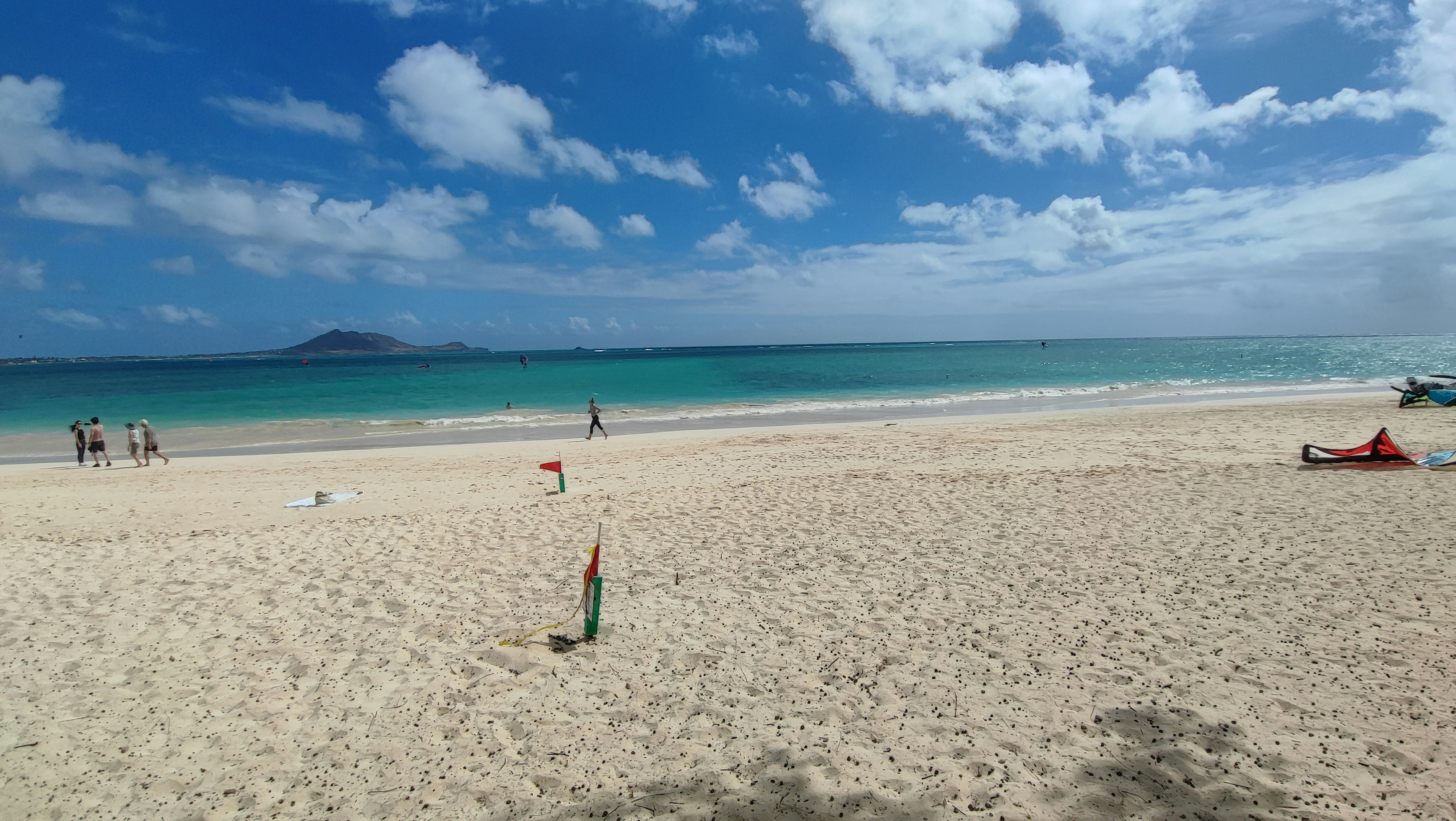 ทิวทัศน์ชายหาดที่สวยงามพร้อมมหาสมุทรสีน้ำเงินและทรายขาวผู้คนพักผ่อนใต้แสงอาทิตย์