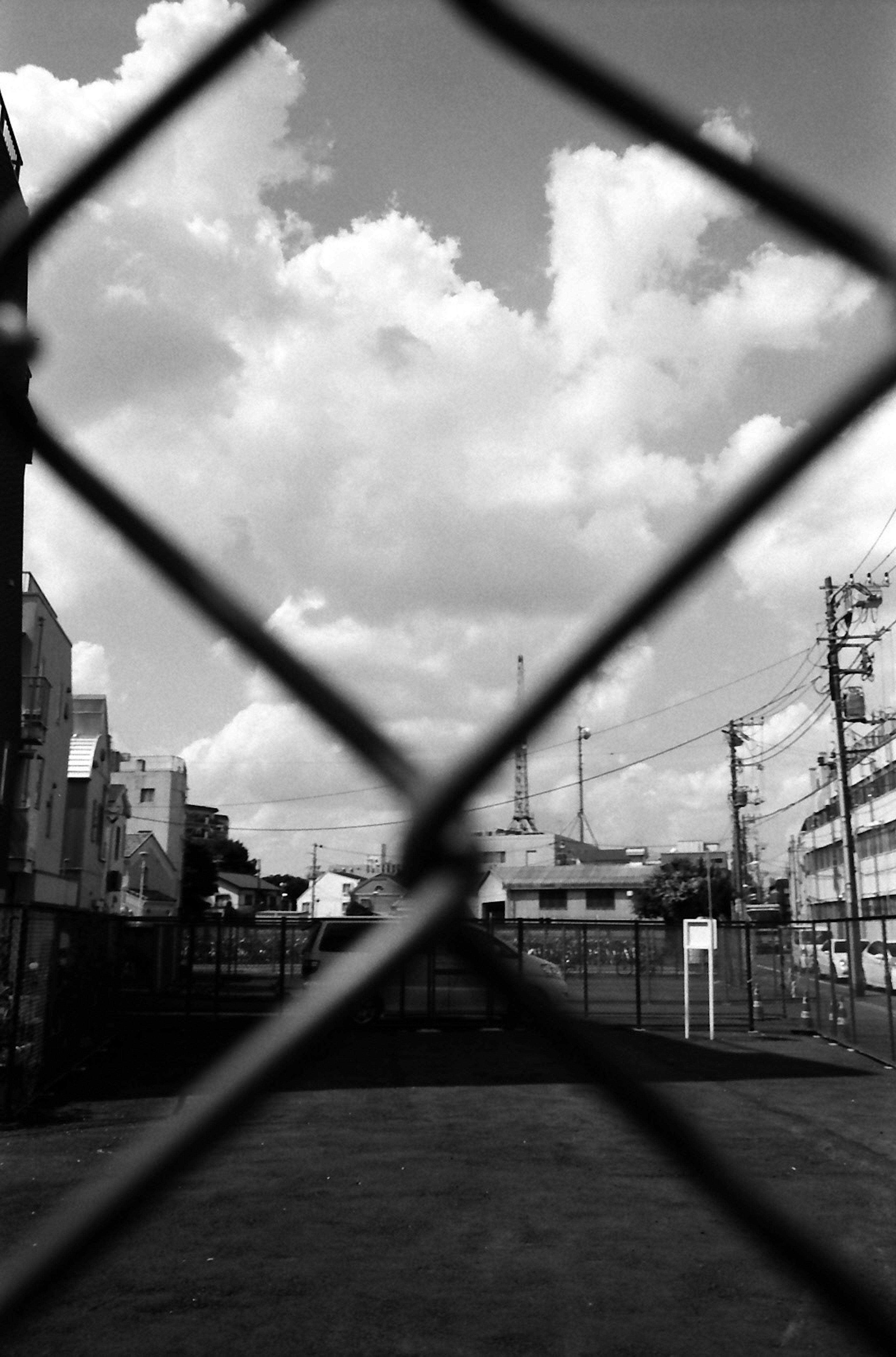 View of the Eiffel Tower through a fence with cloudy sky