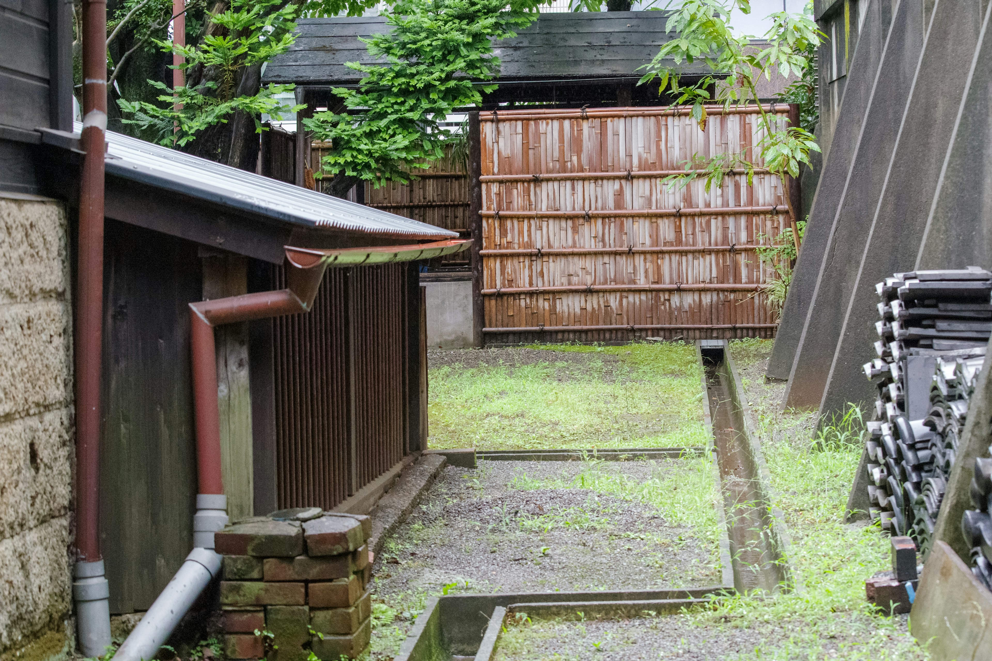 狭い小道の両側にある木製の建物と緑の草地