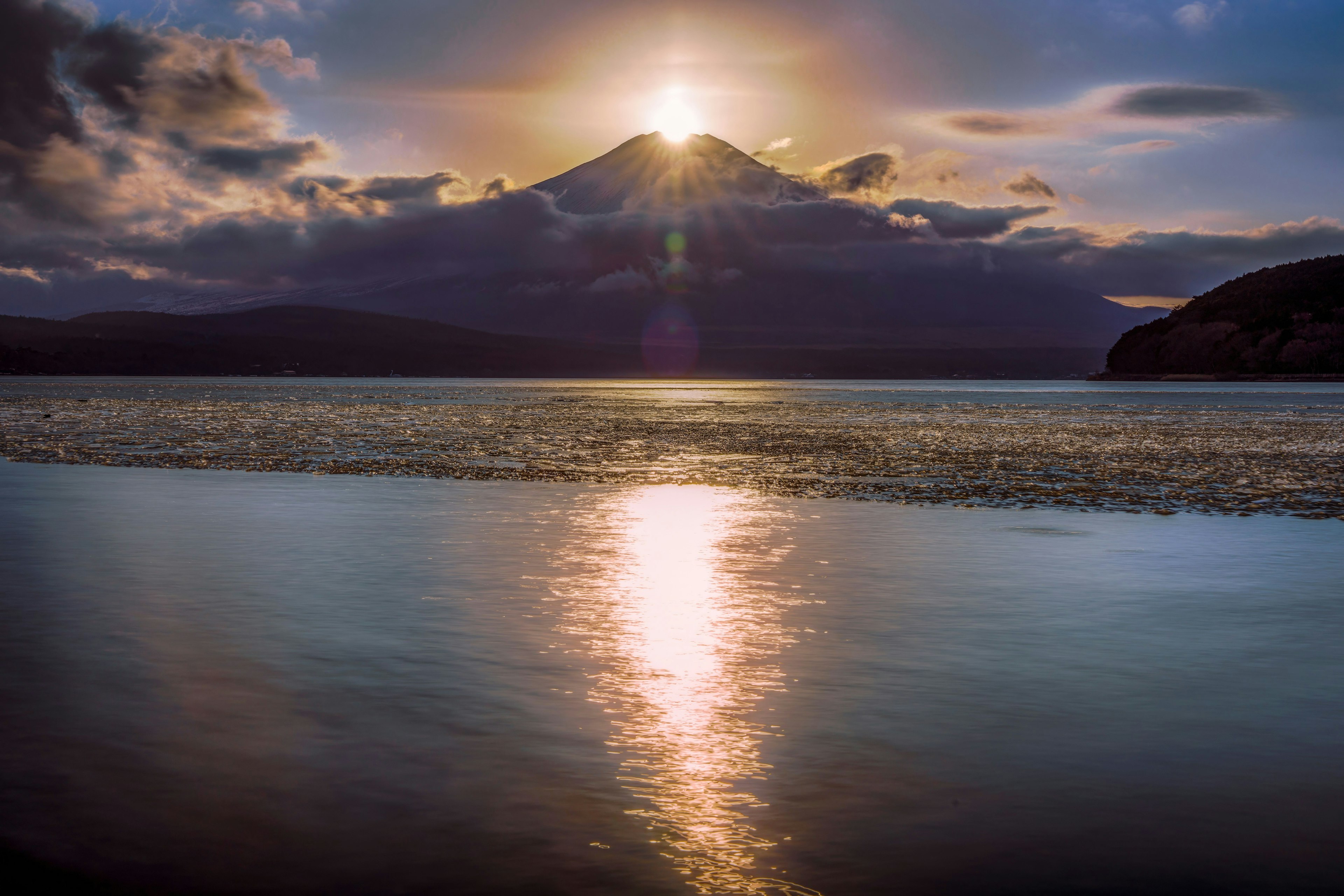 Vue pittoresque d'une montagne avec le soleil se levant au-dessus d'elle se reflétant sur le lac