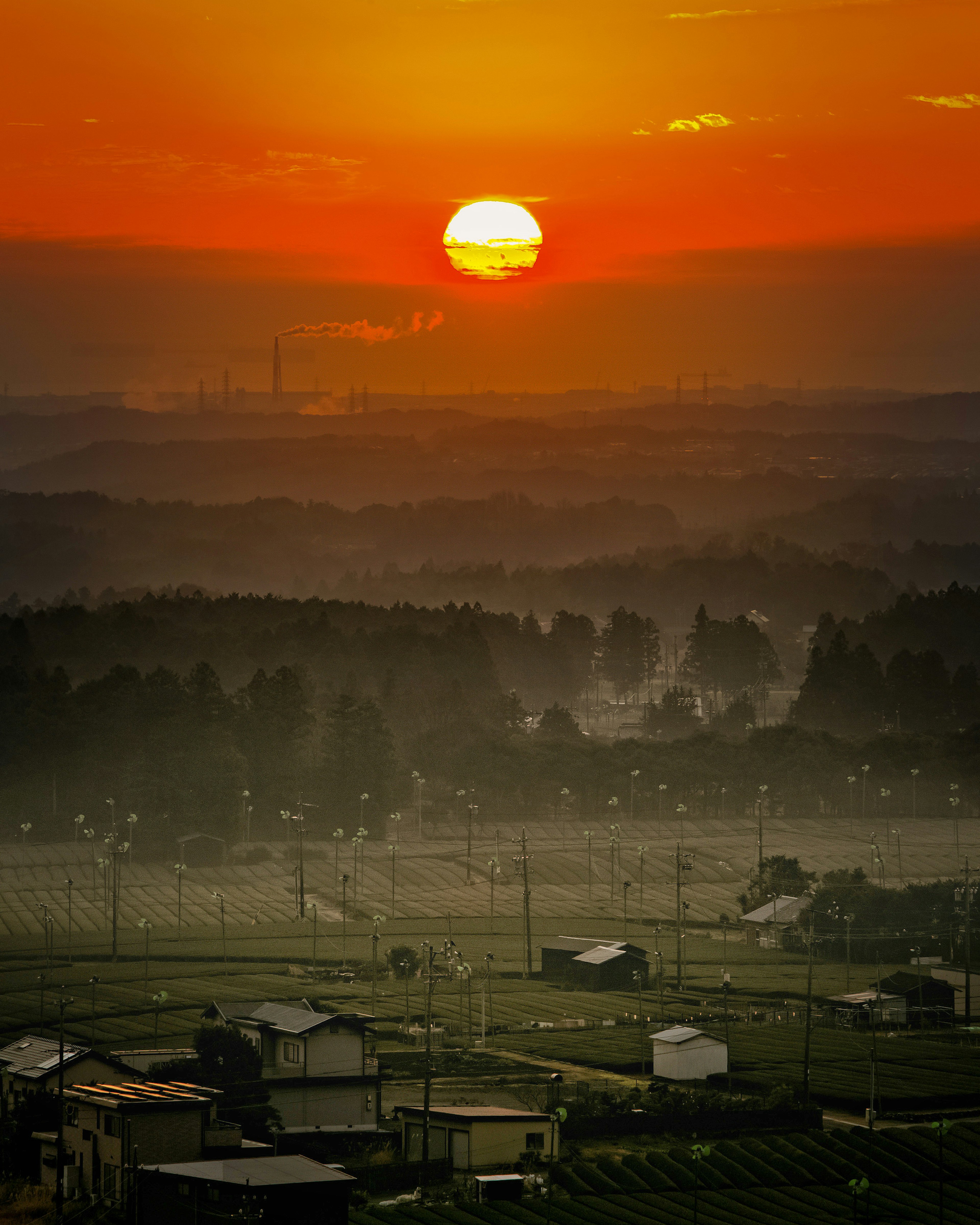 Coucher de soleil sur un paysage rural brumeux avec de petites maisons