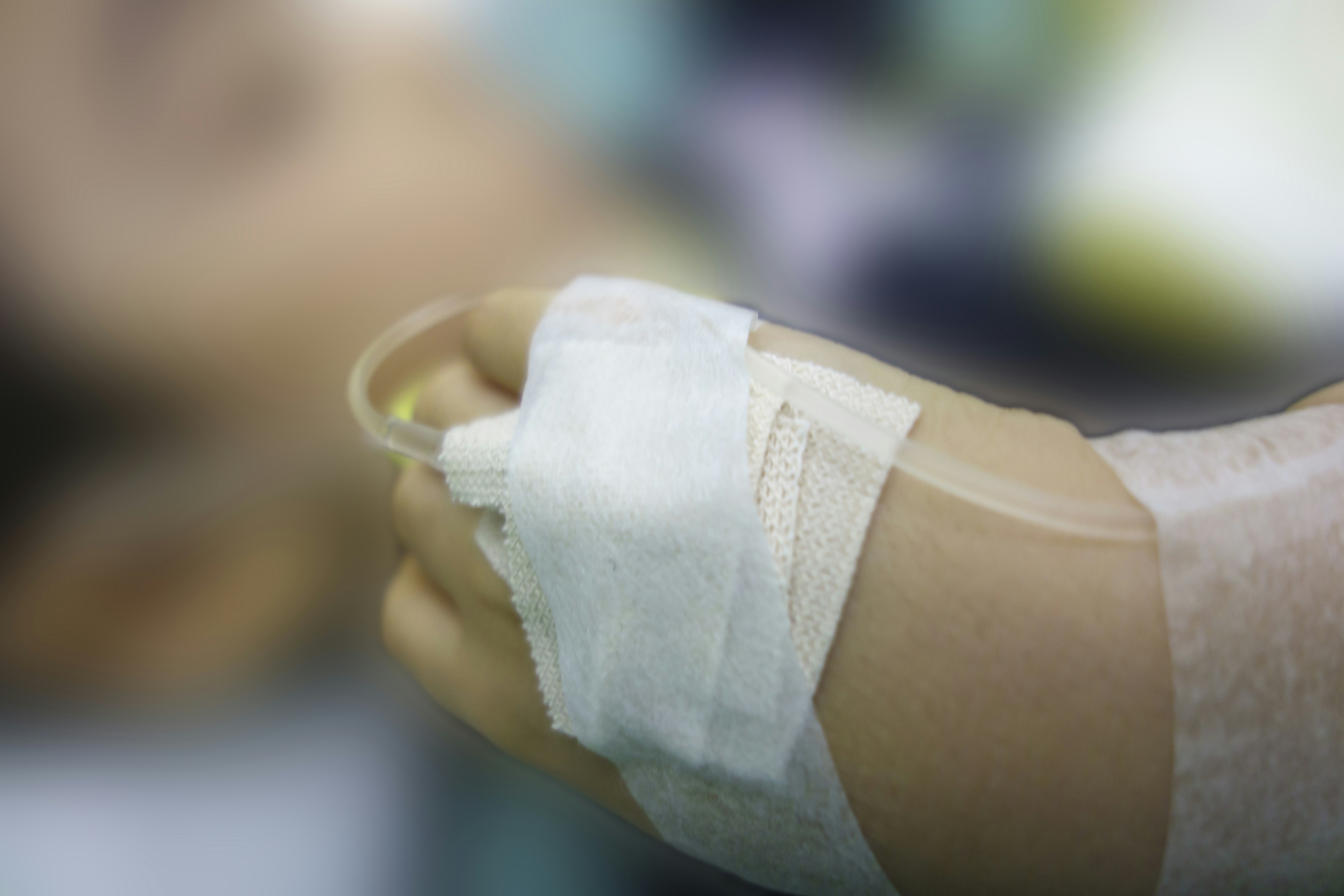 A blurred image showing an IV drip on a patient's arm