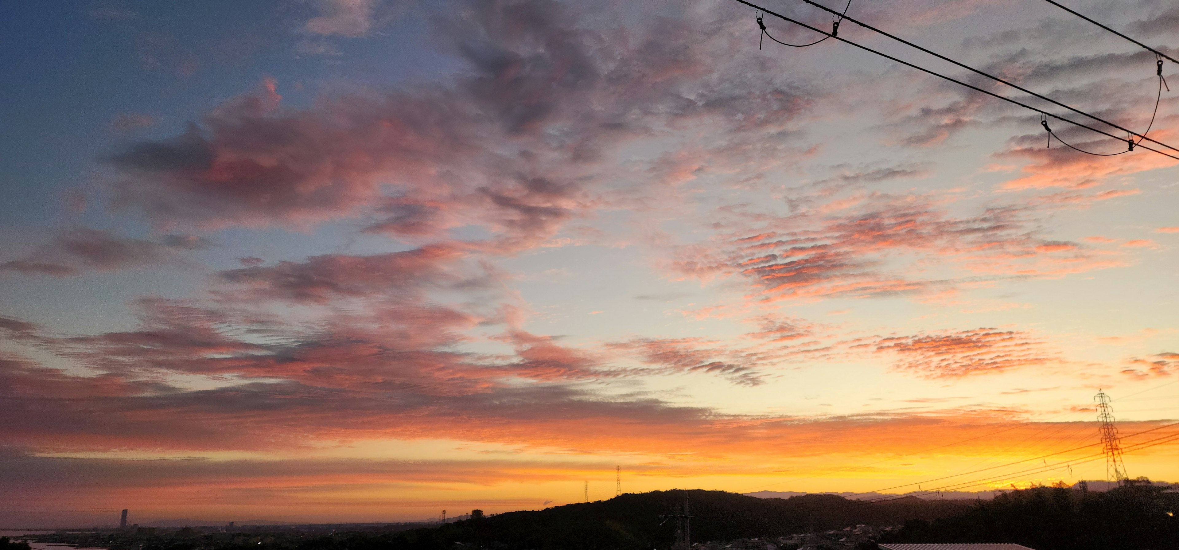 Lebendiger Sonnenuntergangshimmel mit bunten Wolken und silhouettierten Hügeln