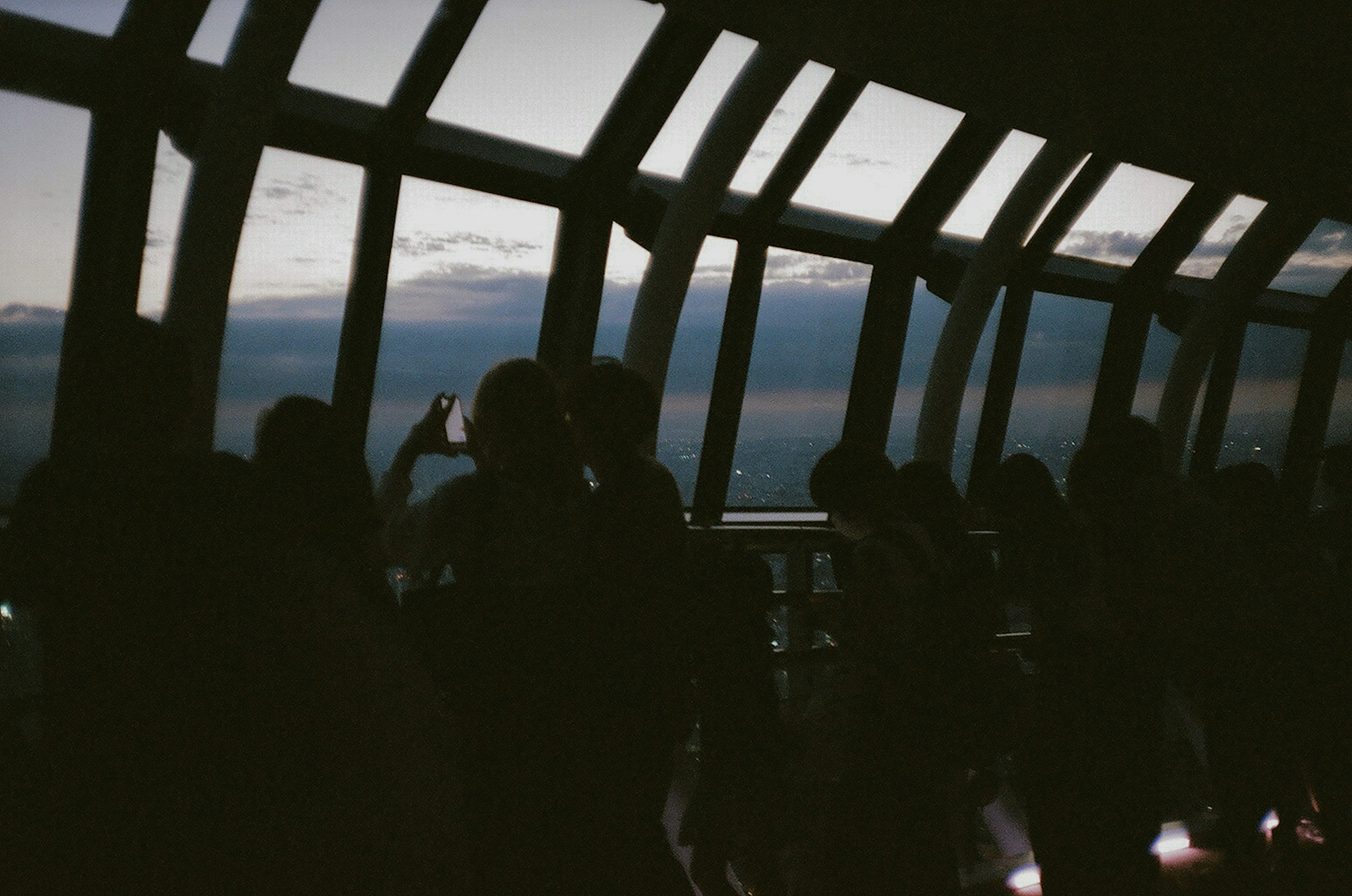 Silhouetted people enjoying the night view by the windows