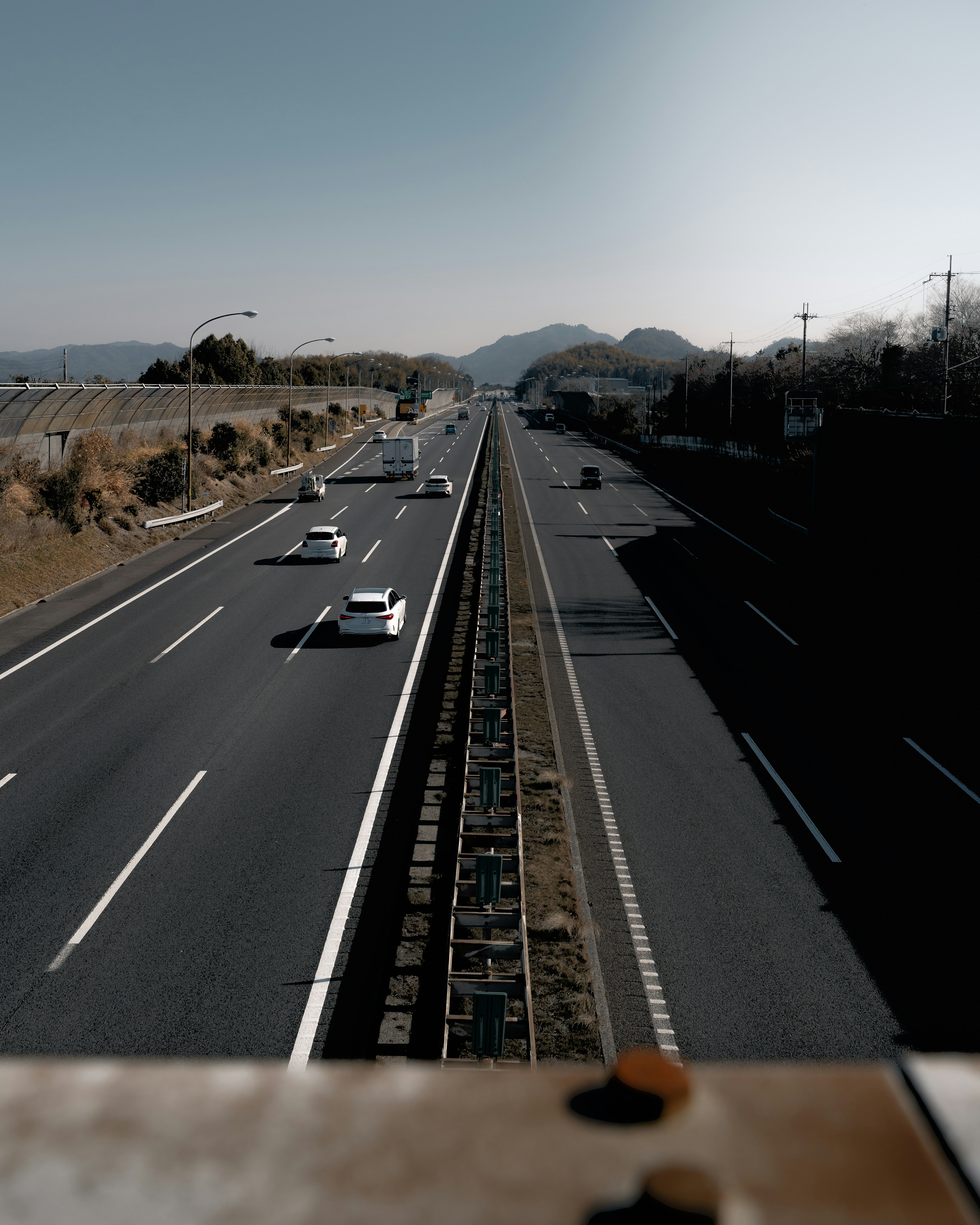 A view from above the highway showing cars driving with mountains in the background