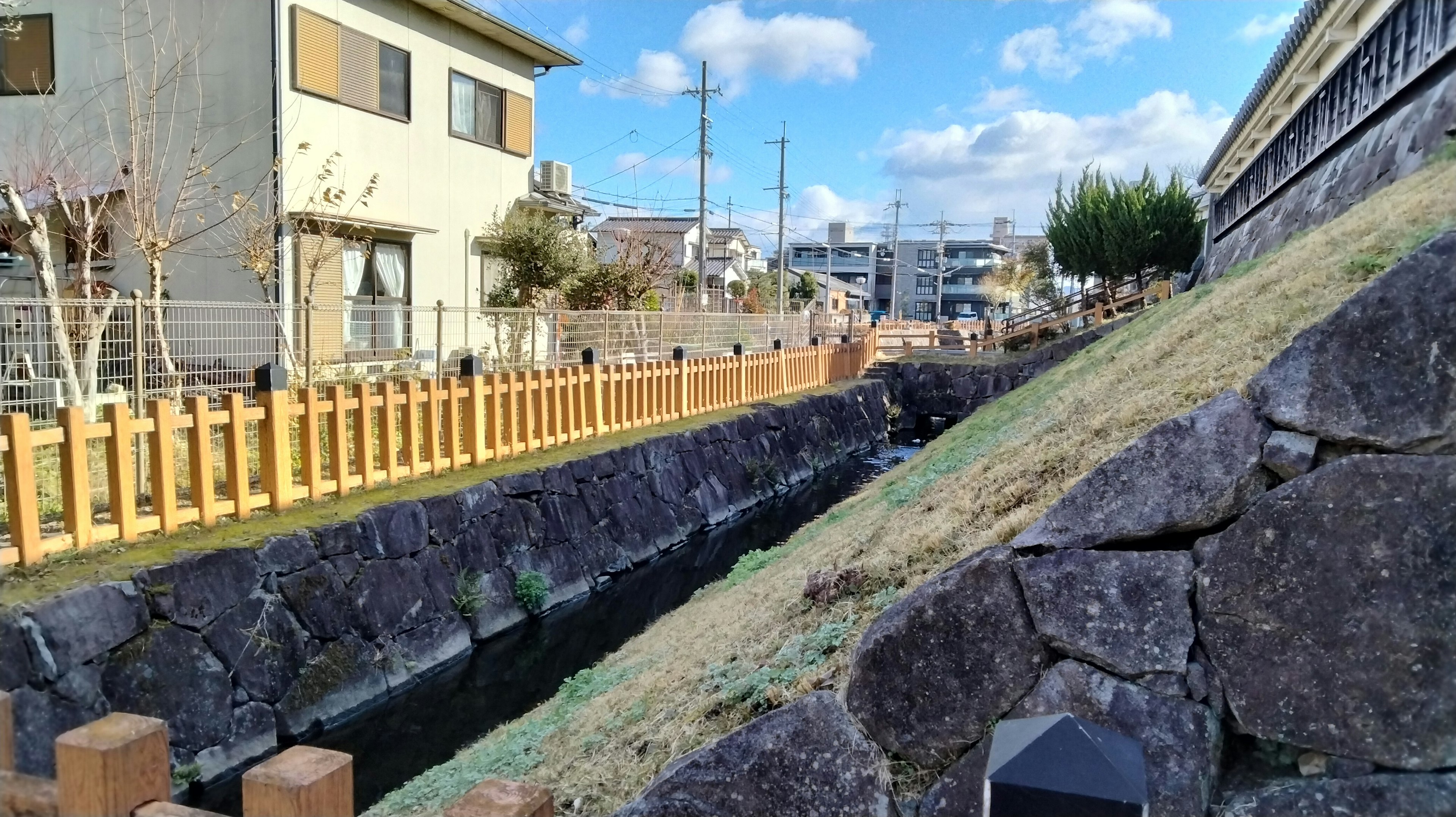 Scenic view of a quiet neighborhood featuring a stone wall and a narrow stream