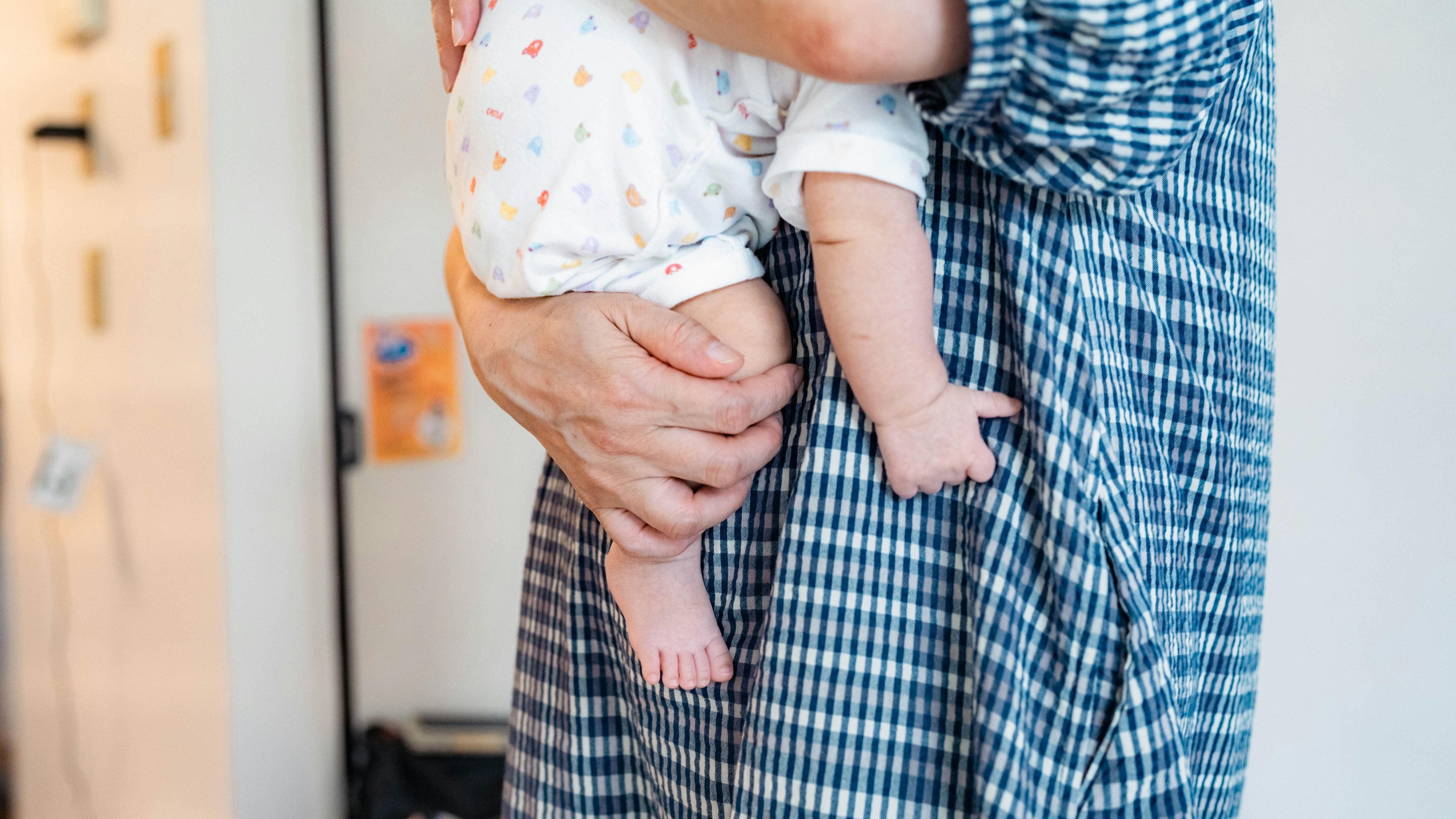 Image of a person holding a baby with distinctive checkered clothing