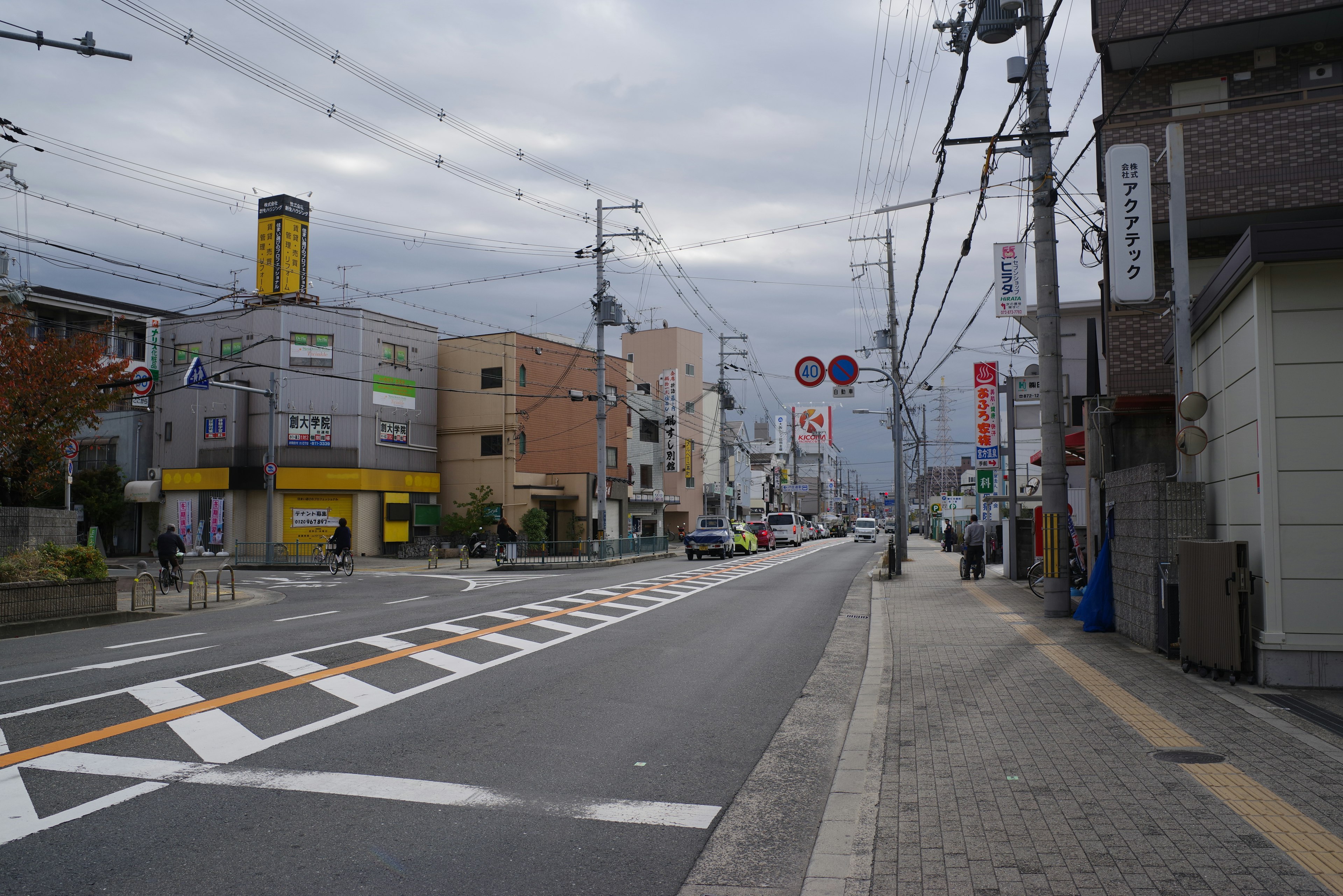 Pemandangan jalan di Jepang di bawah langit mendung menampilkan gedung komersial dan rambu jalan