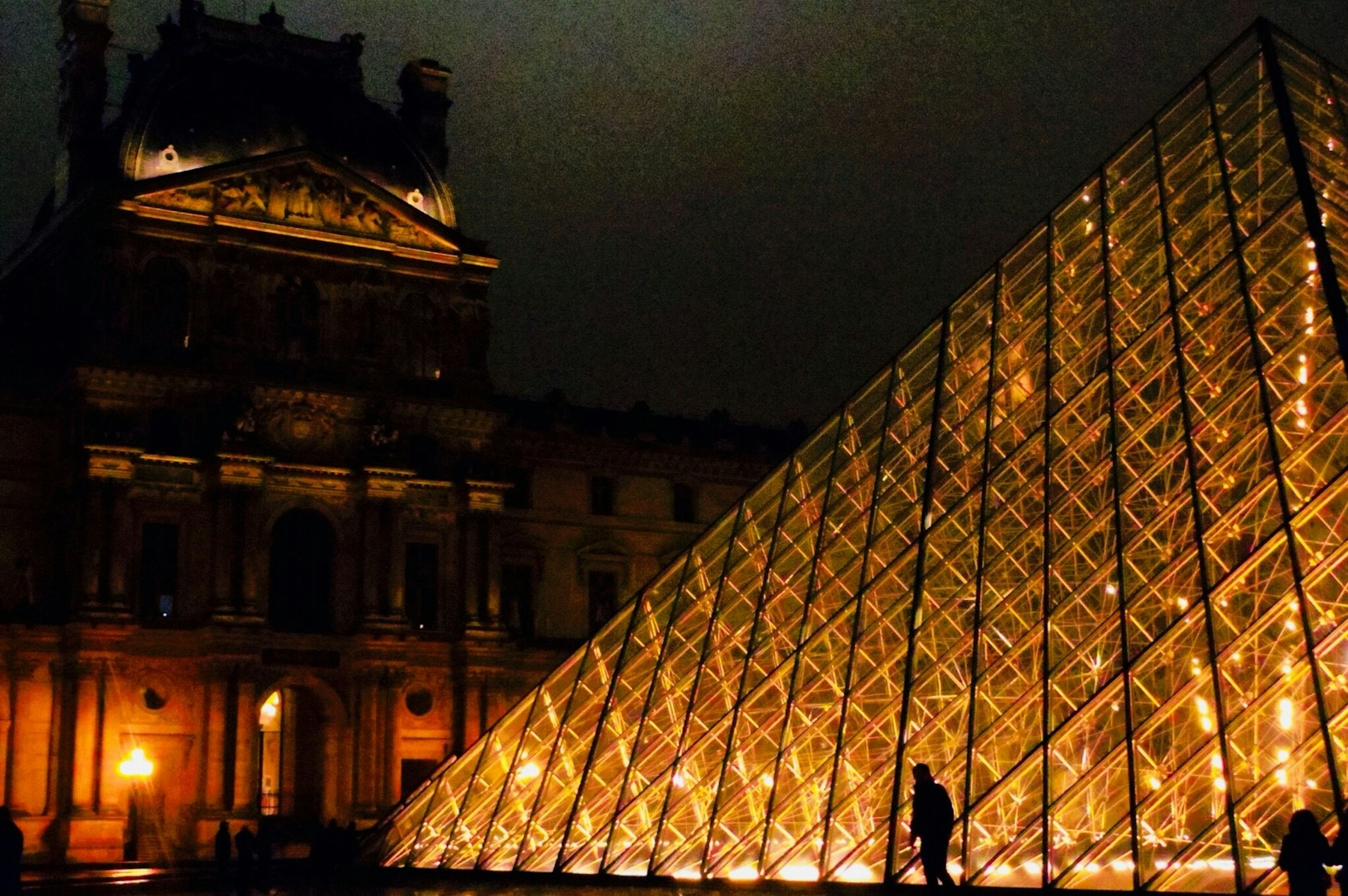 Vista nocturna del Museo del Louvre con la pirámide de vidrio bellamente iluminada