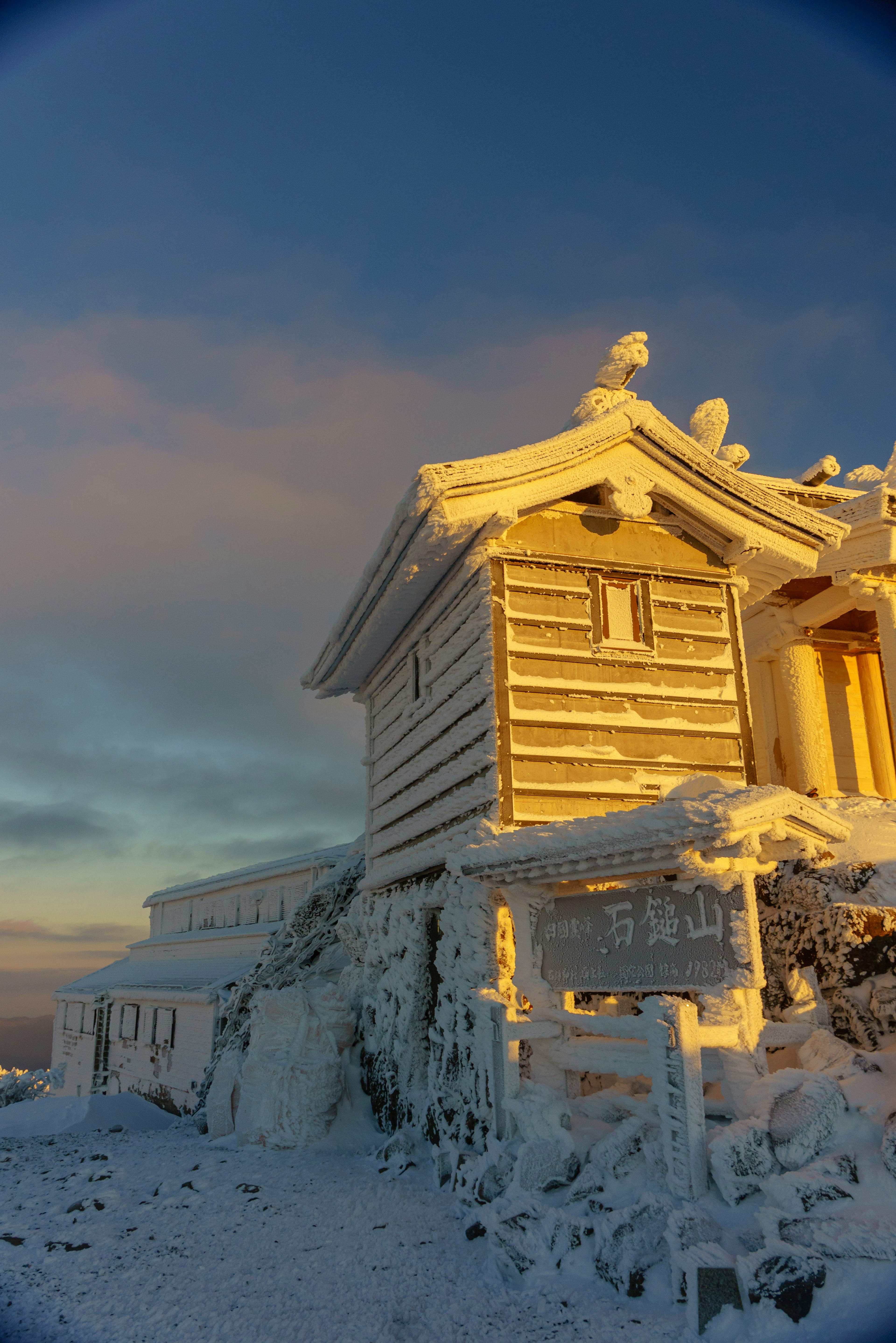 一座被雪覆蓋的神社建築沐浴在金色的夕陽光輝中