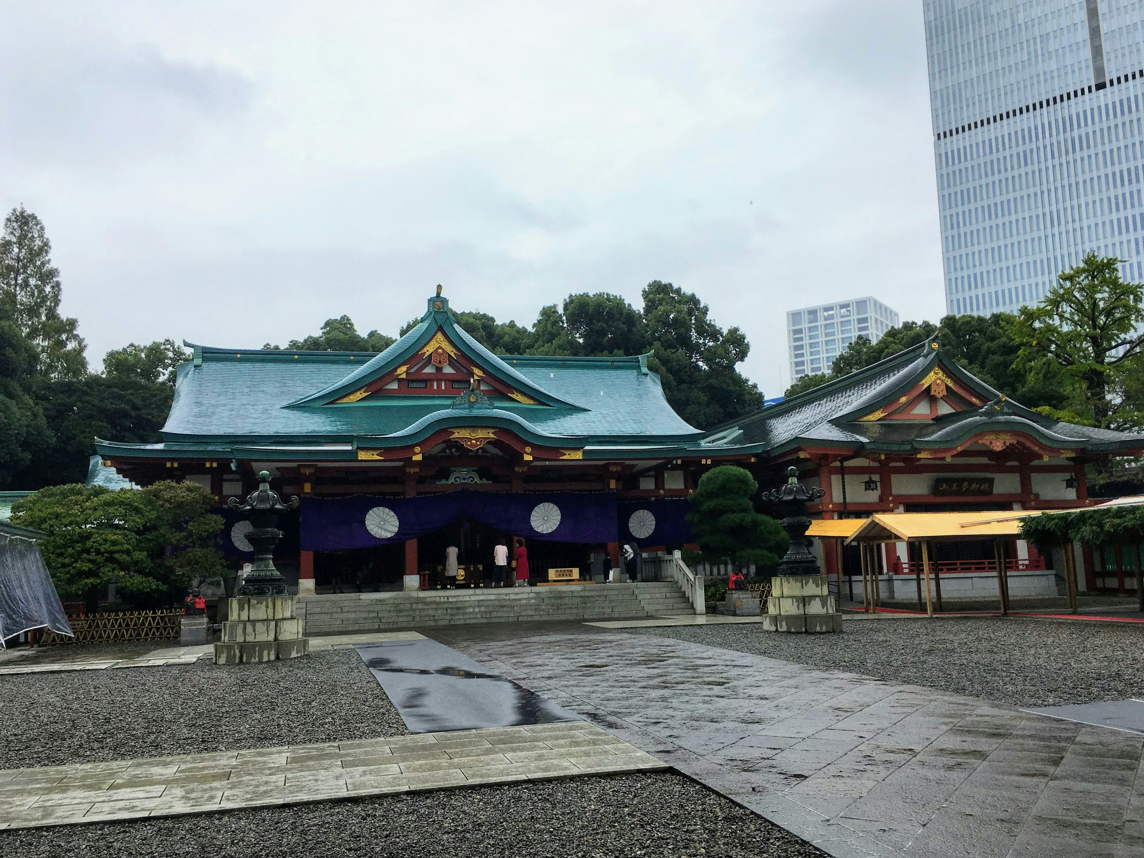 Serene shrine scene featuring blue roofs and white curtains in the rain