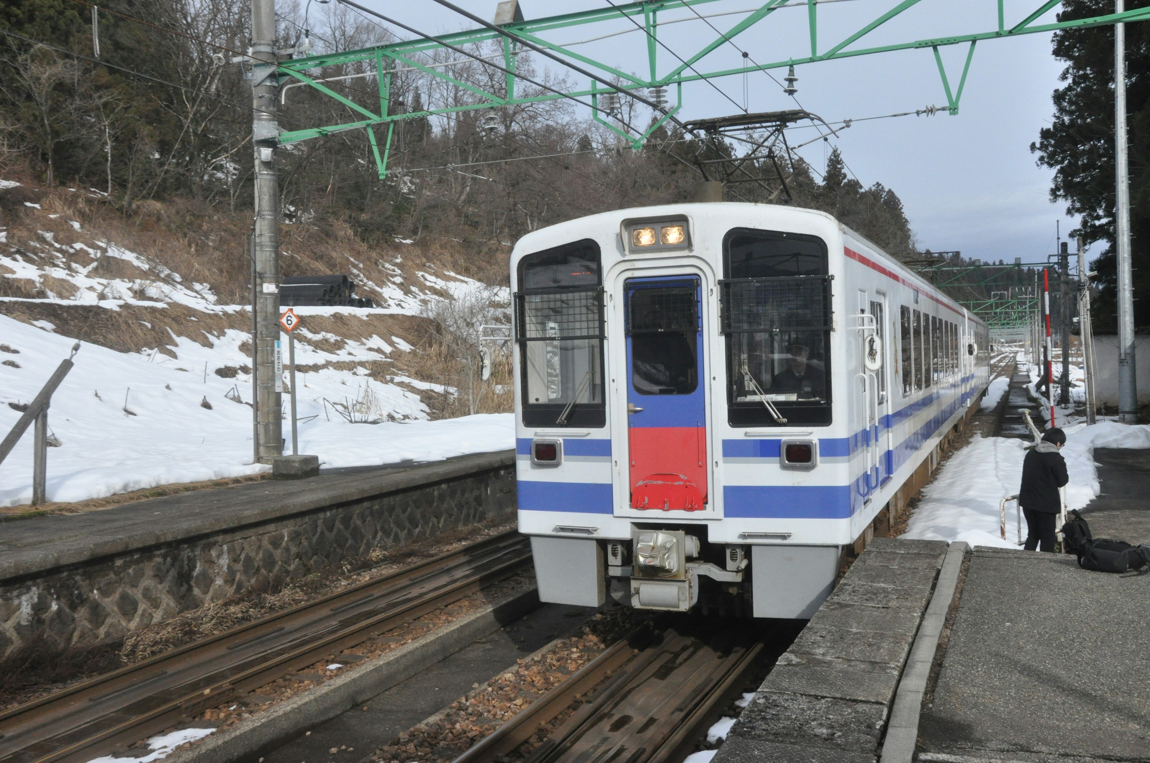 Kereta berhenti di stasiun bersalju dikelilingi bukit