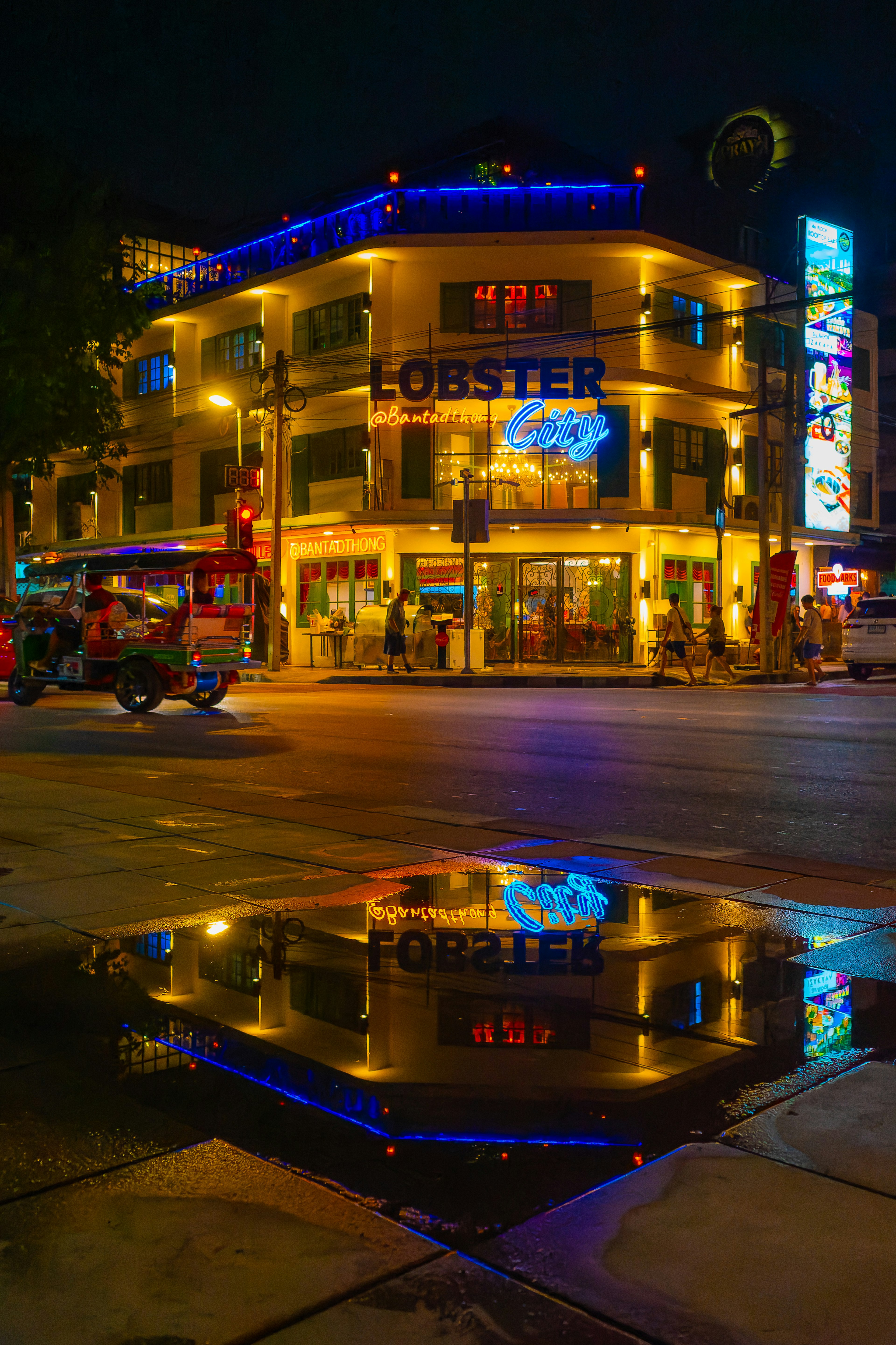 Building with Lobster sign illuminated at night reflecting in puddle