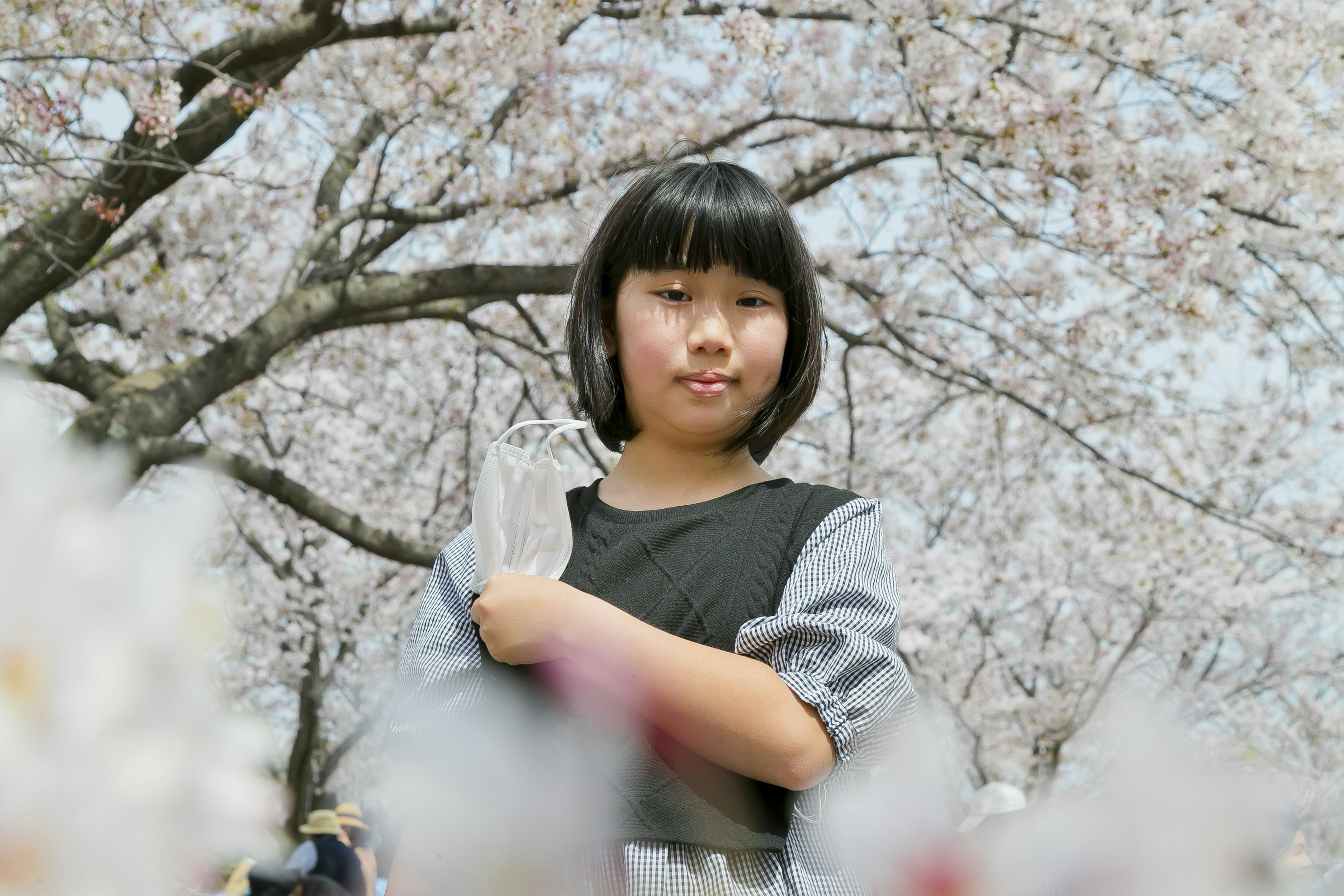 Fille souriante sous un cerisier en fleurs avec des fleurs au premier plan