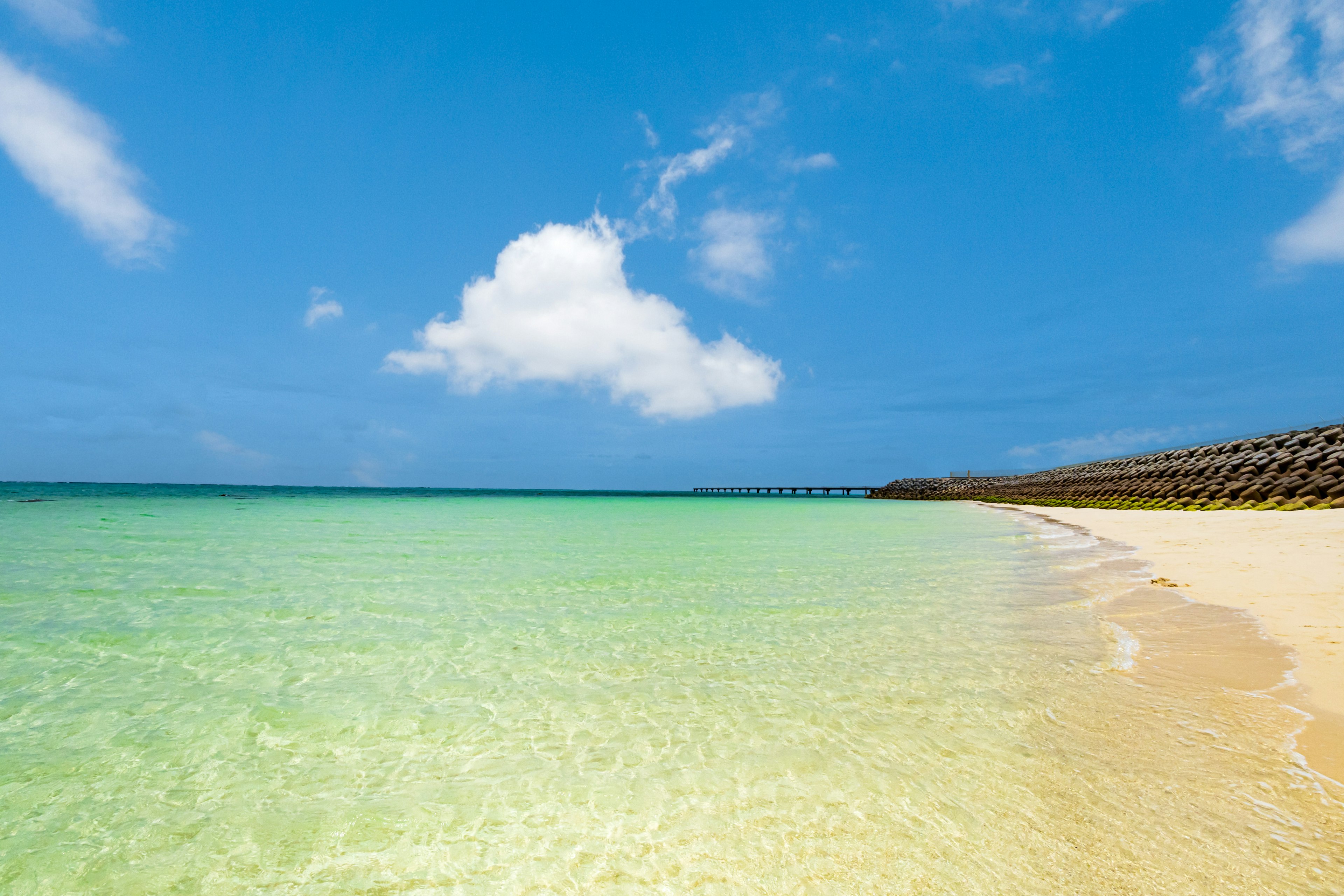 Strandszene mit klarem türkisfarbenem Wasser und blauem Himmel