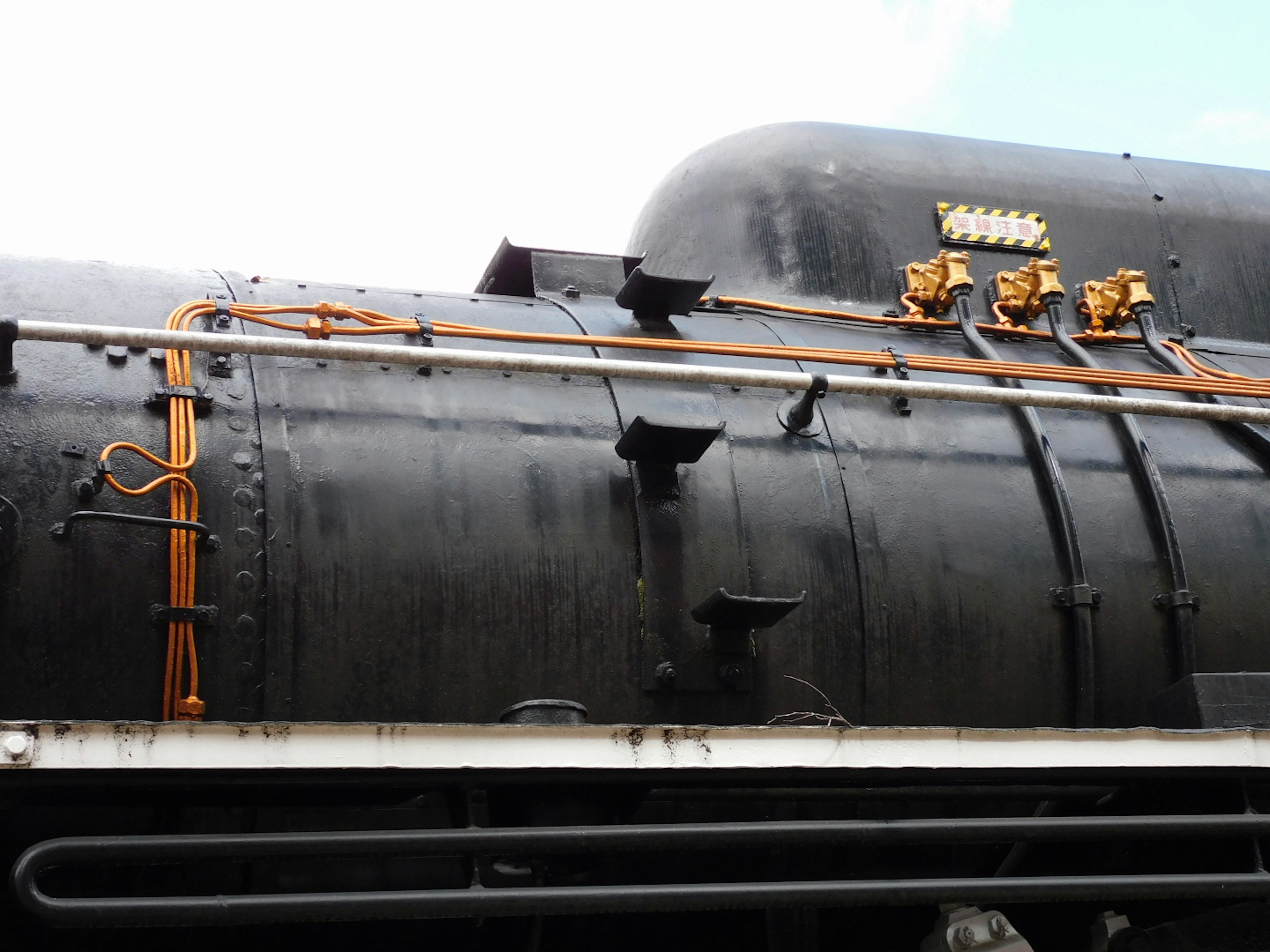 Side view of a black steam locomotive featuring metal pipes and decorative elements