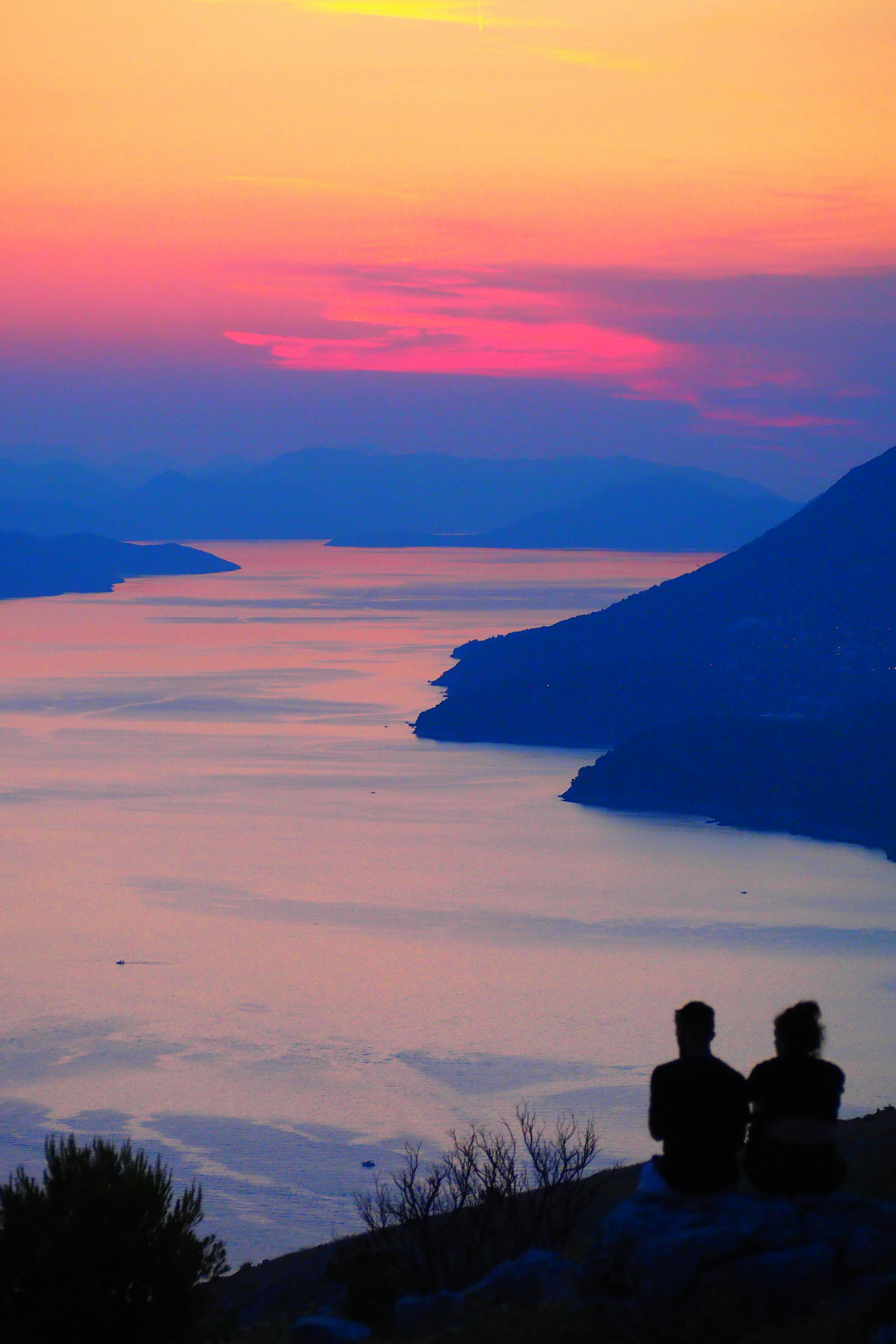 Silhouette di due persone che guardano un tramonto su un lago