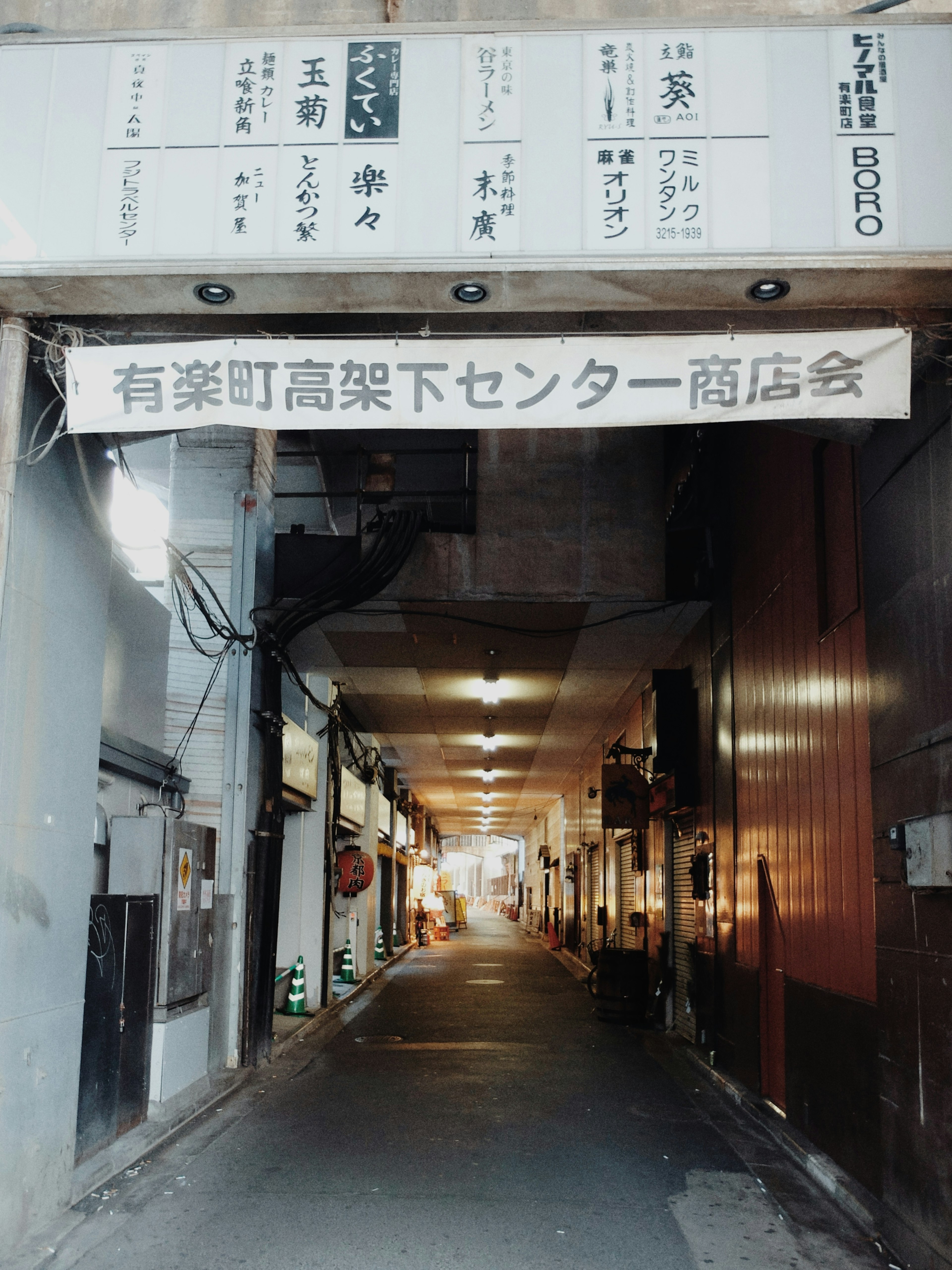 Foto jalan perbelanjaan di Yurakucho dengan toko di kedua sisi dan pencahayaan cerah