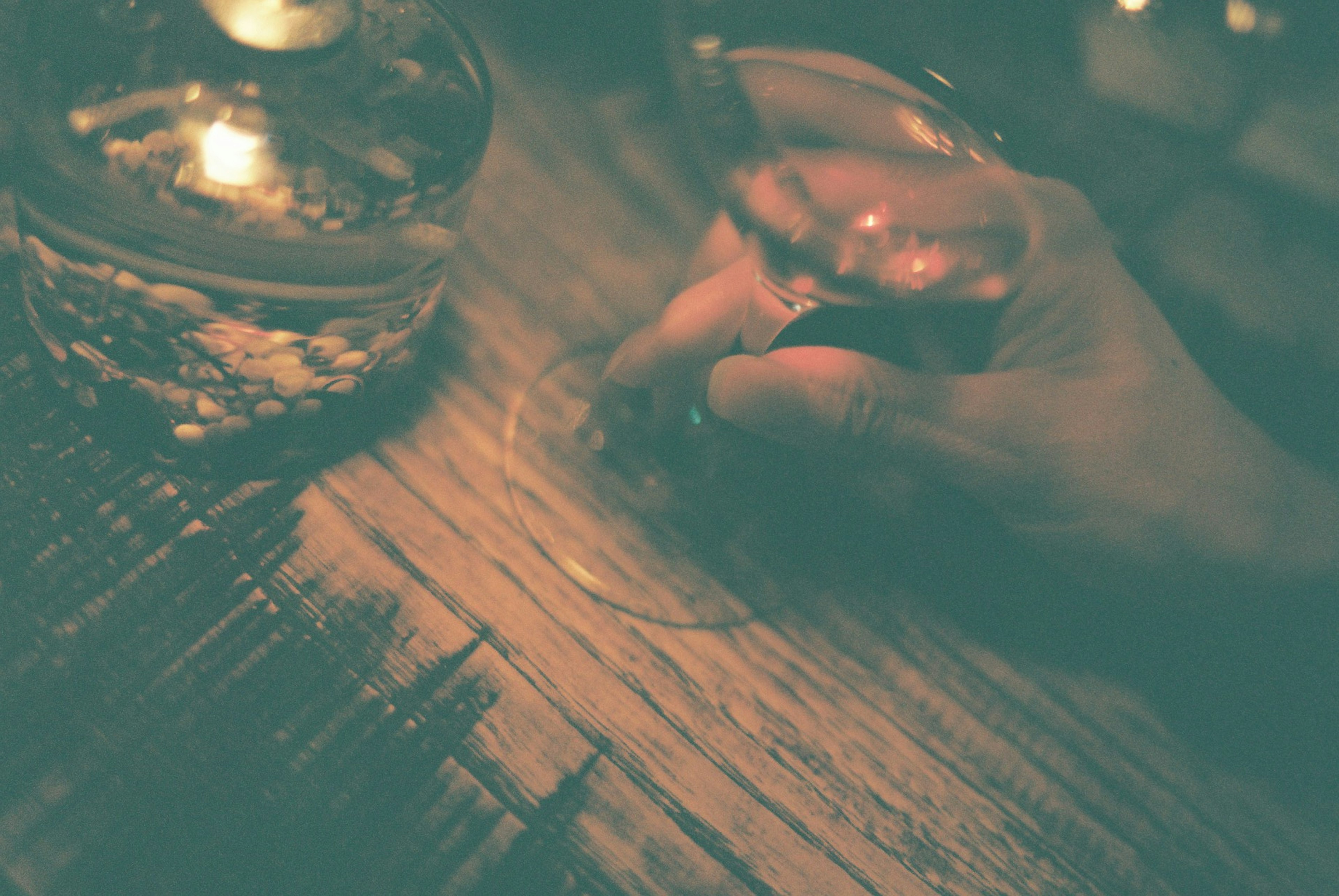 A hand holding a pen near a glass on a wooden table