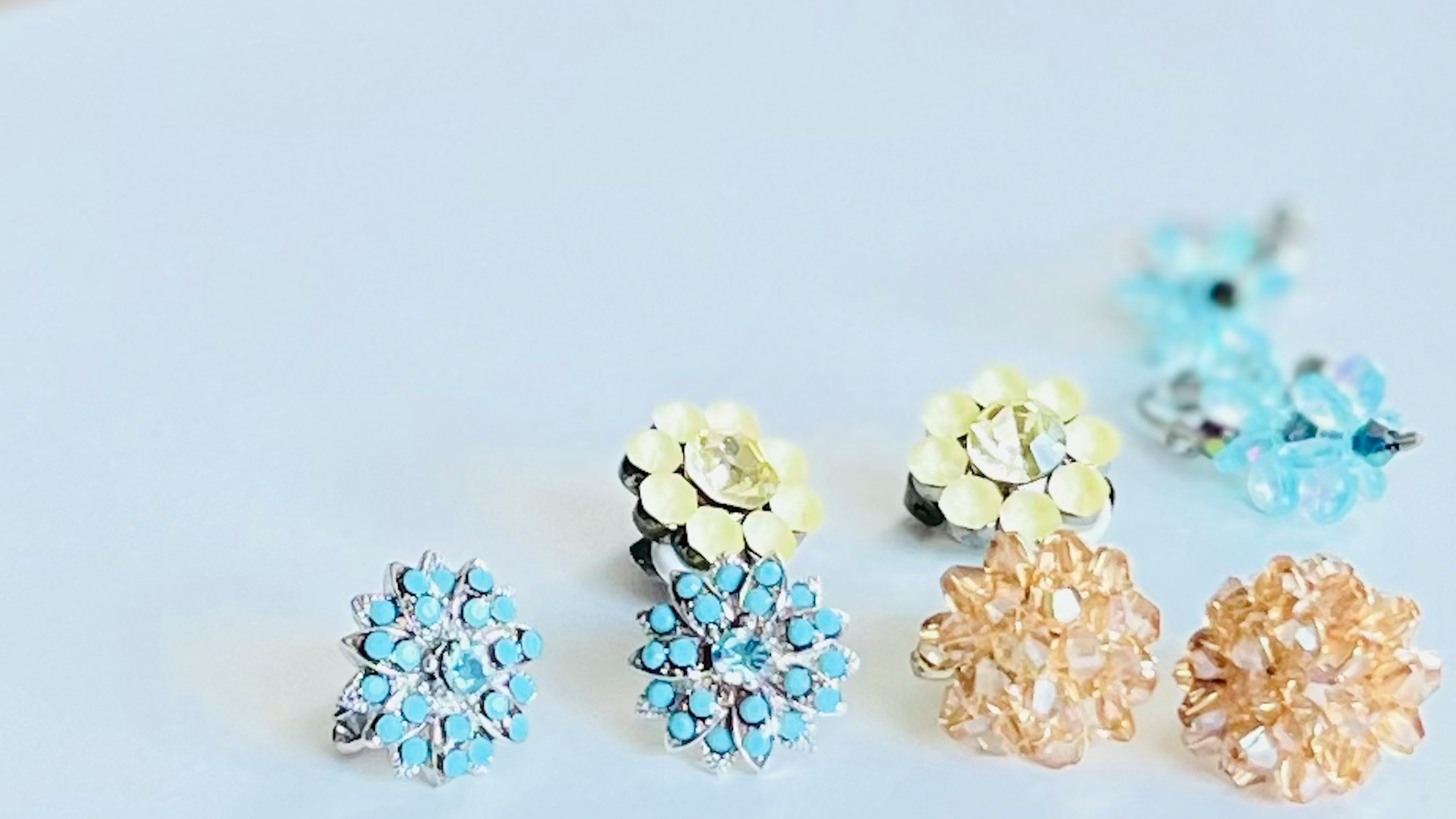 Flower-shaped earrings in blue and gold arranged on a surface