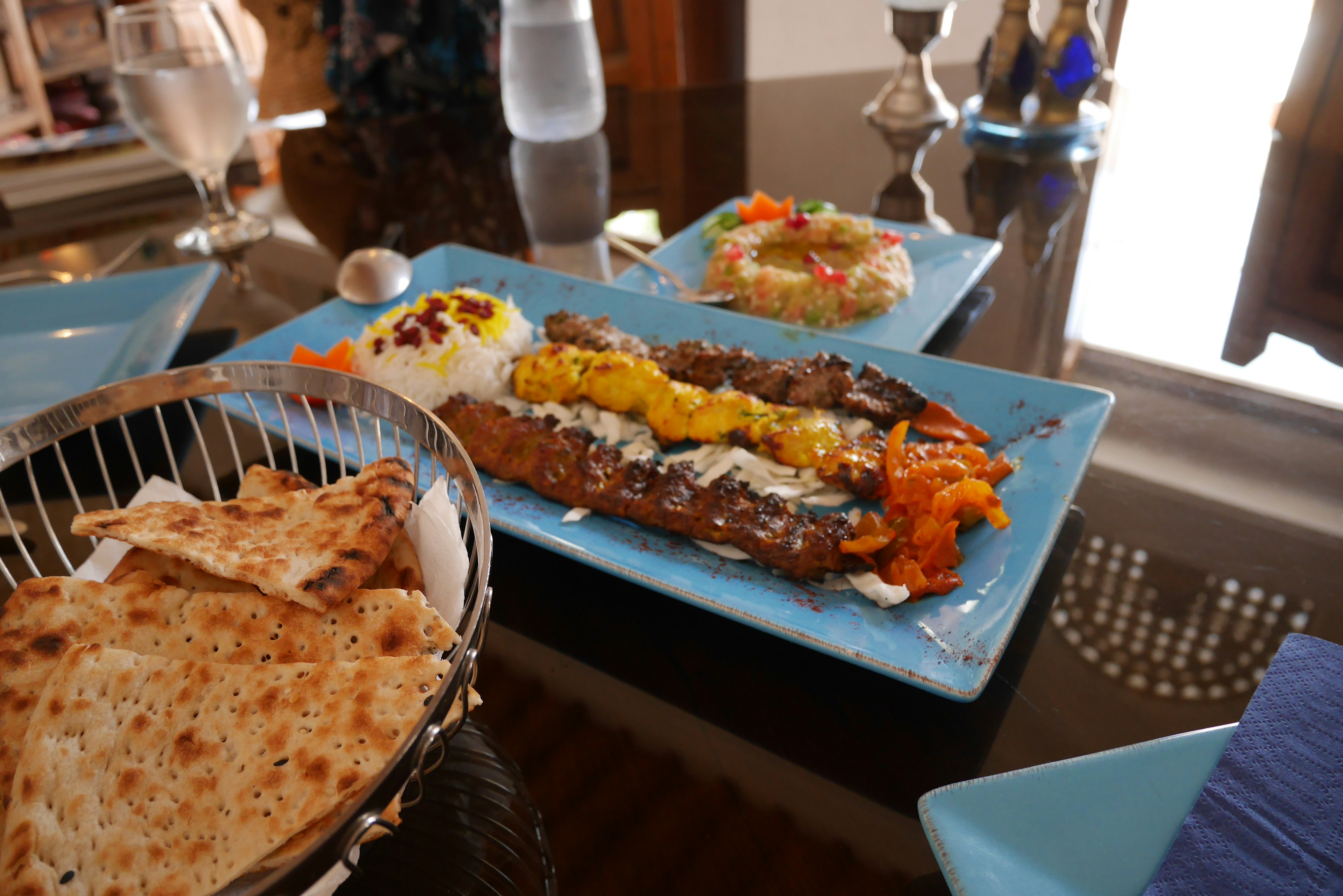 Turkish kebab dish served on a blue plate with naan bread and salad