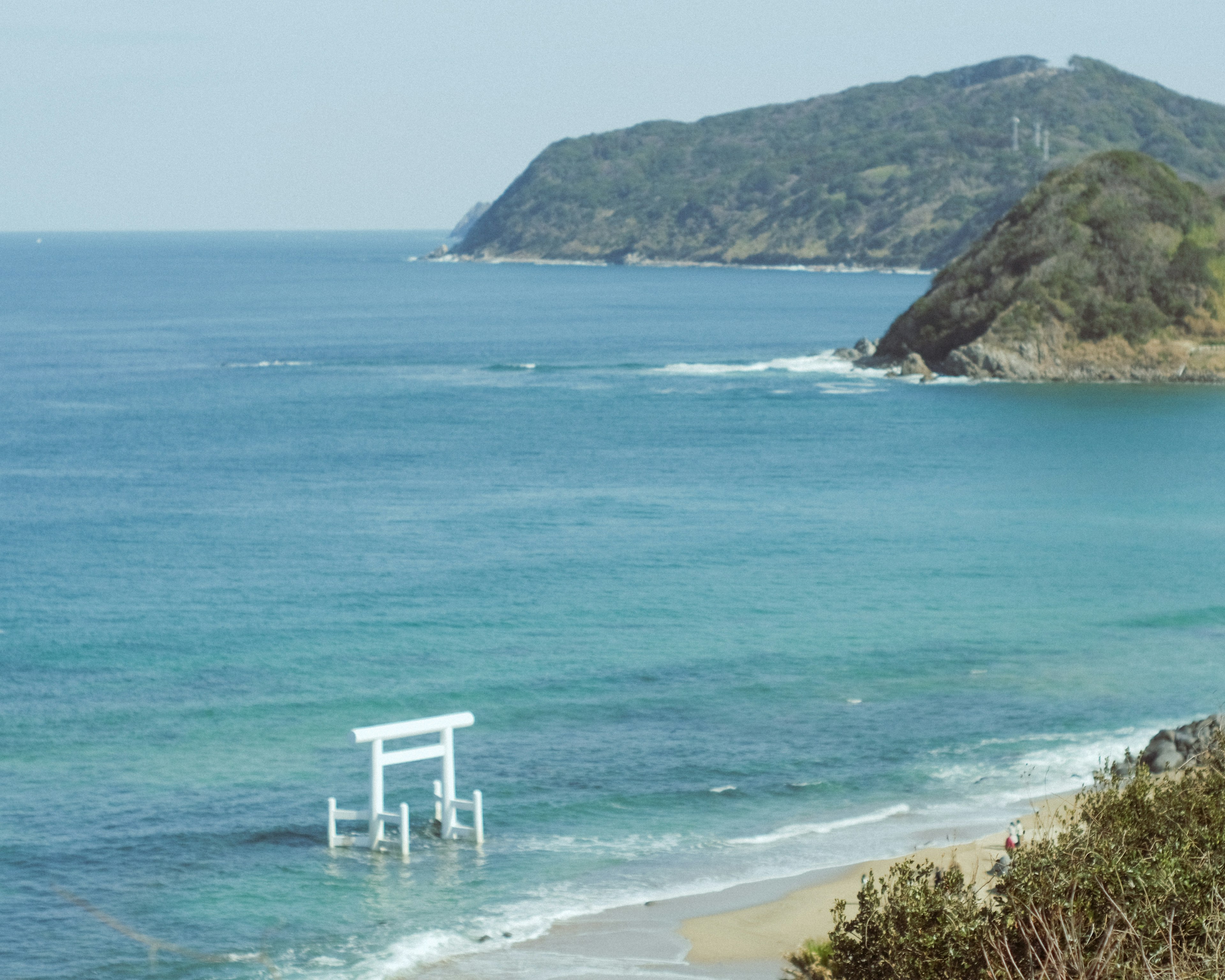 Vista costera con mar azul y puerta torii blanca