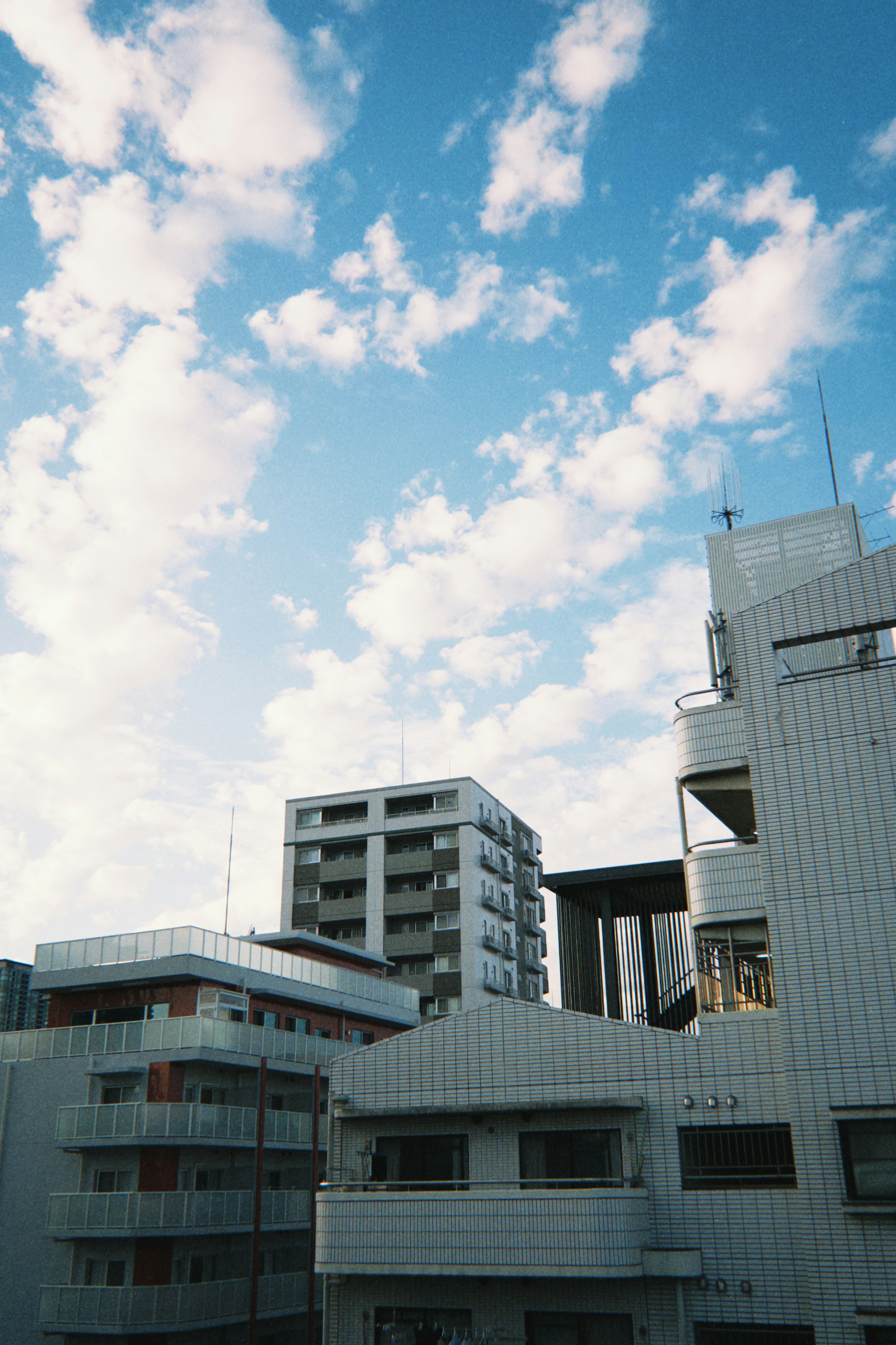 Pemandangan gedung modern di bawah langit biru dengan awan putih