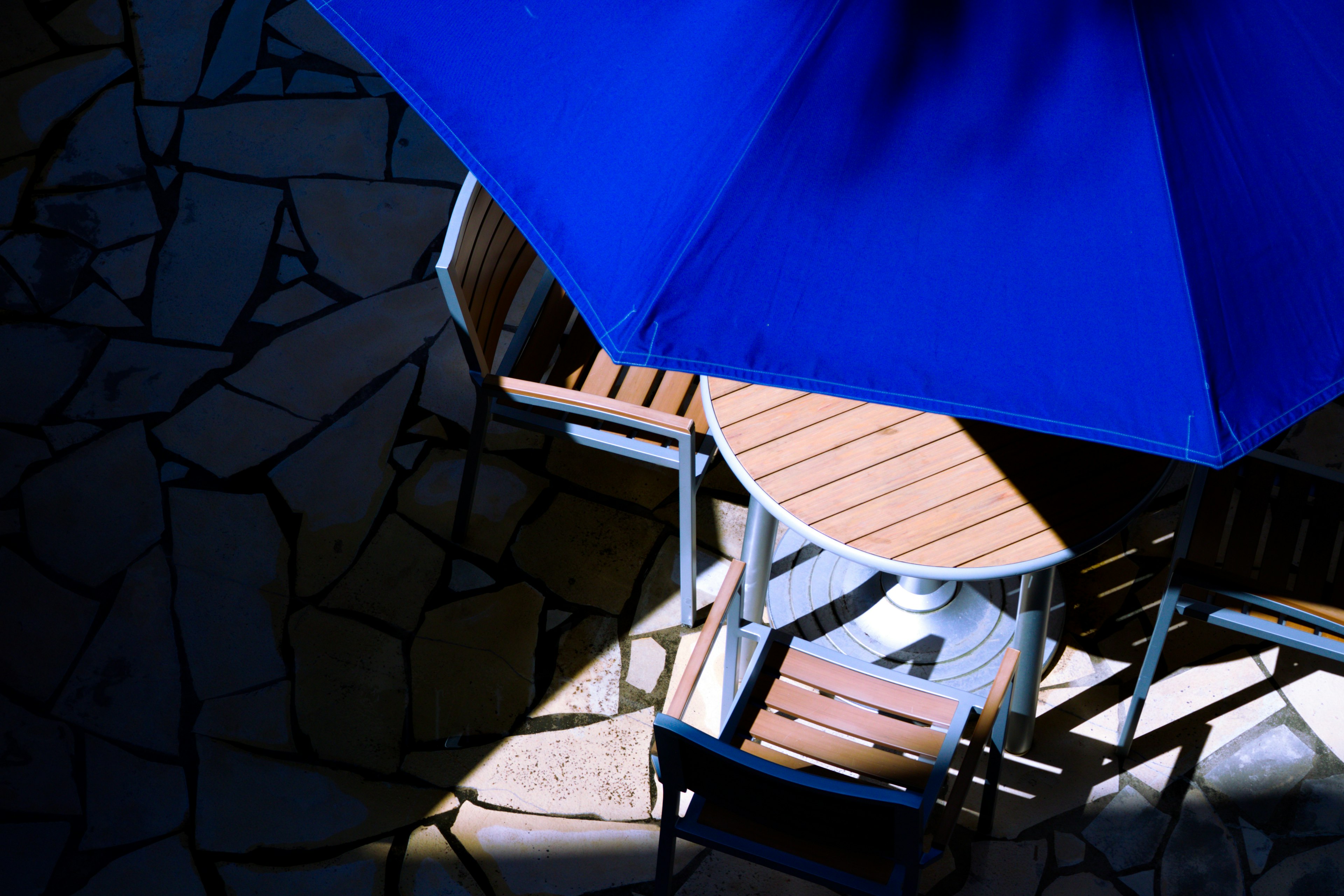 Ensemble de table et chaises en bois sous un parasol bleu