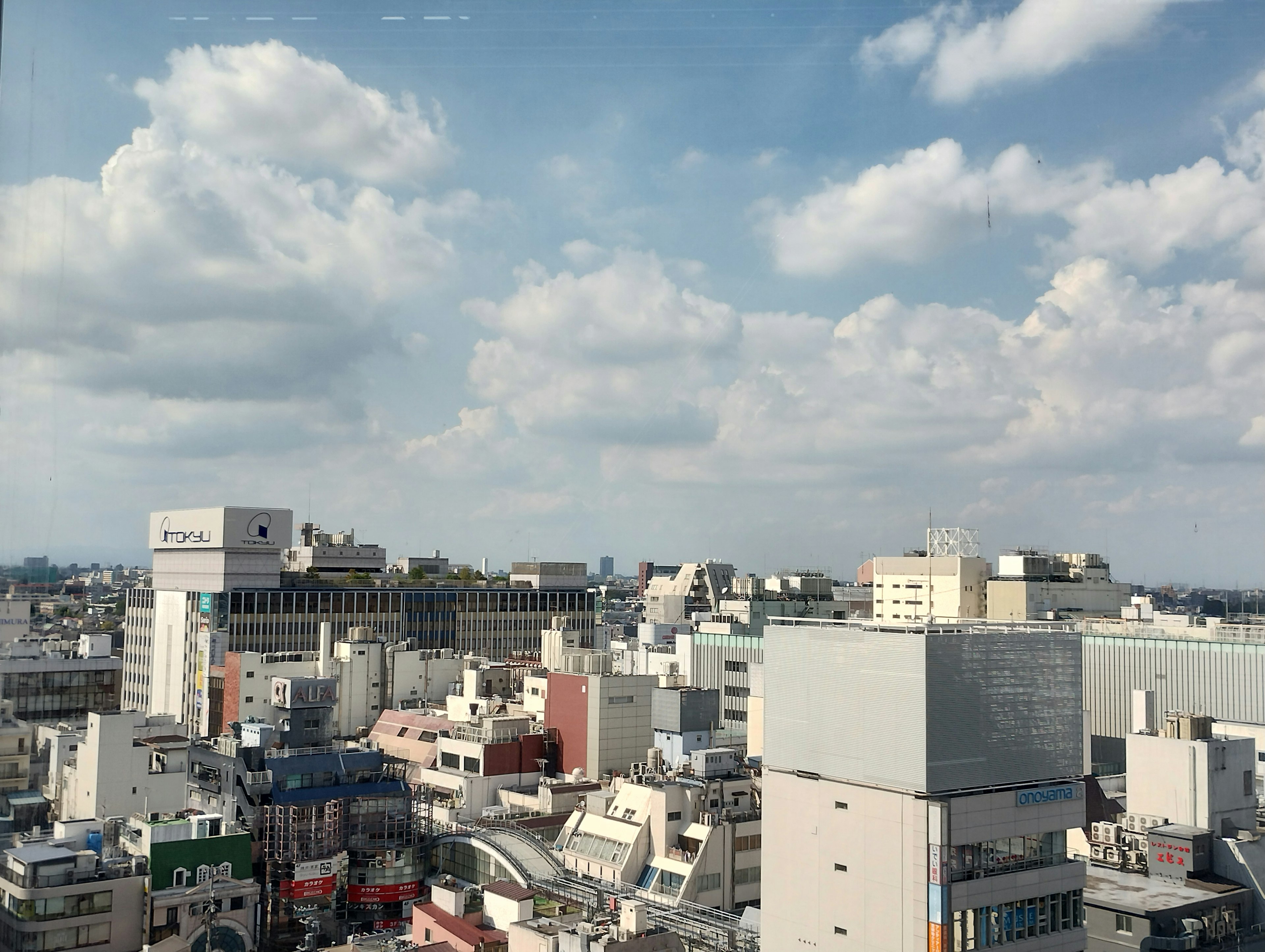 Paisaje urbano con edificios altos y nubes blancas en un cielo azul