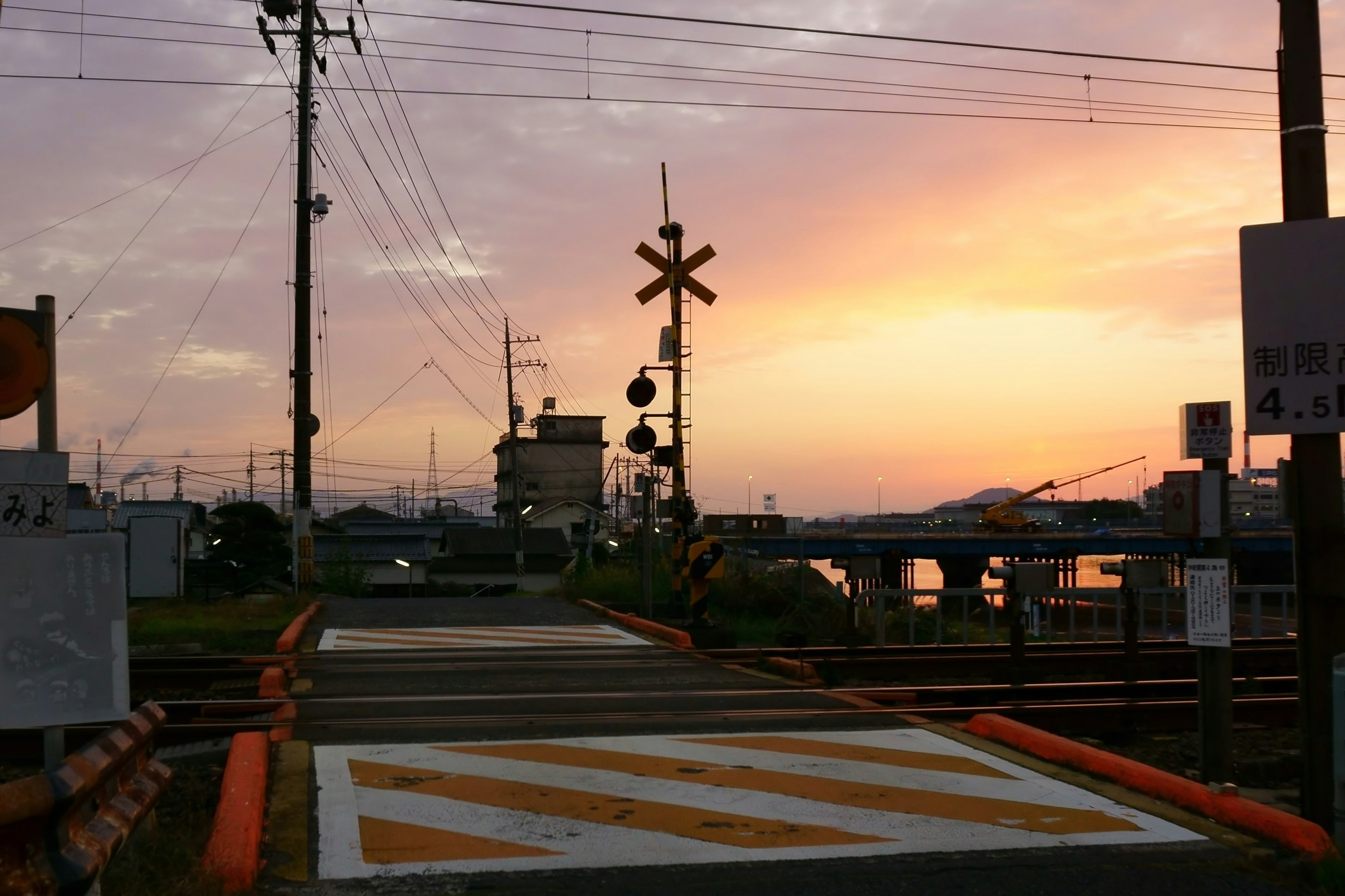 夕焼けの中の鉄道踏切と信号機