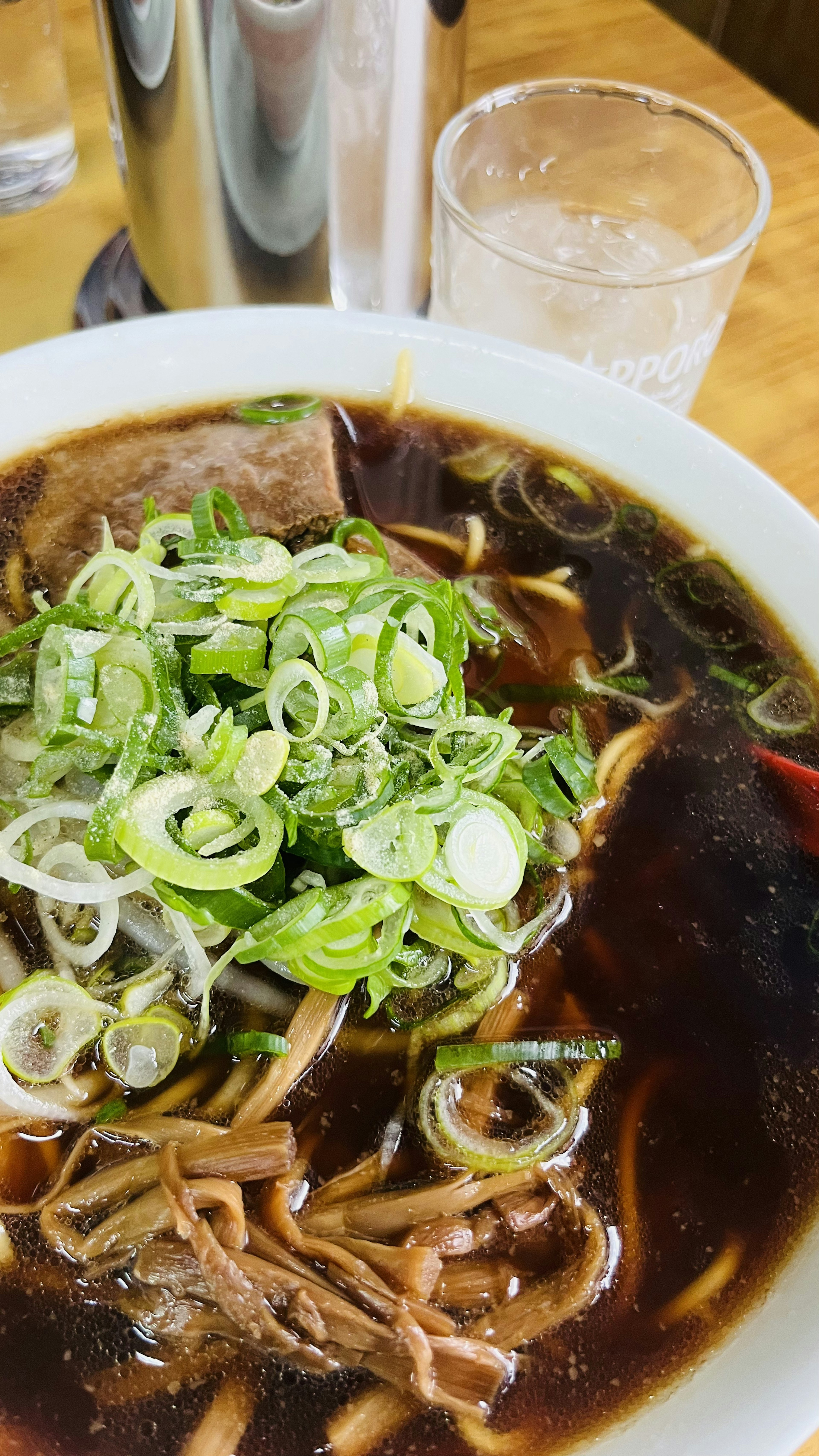 黒いスープのラーメンにネギがたっぷり乗っている