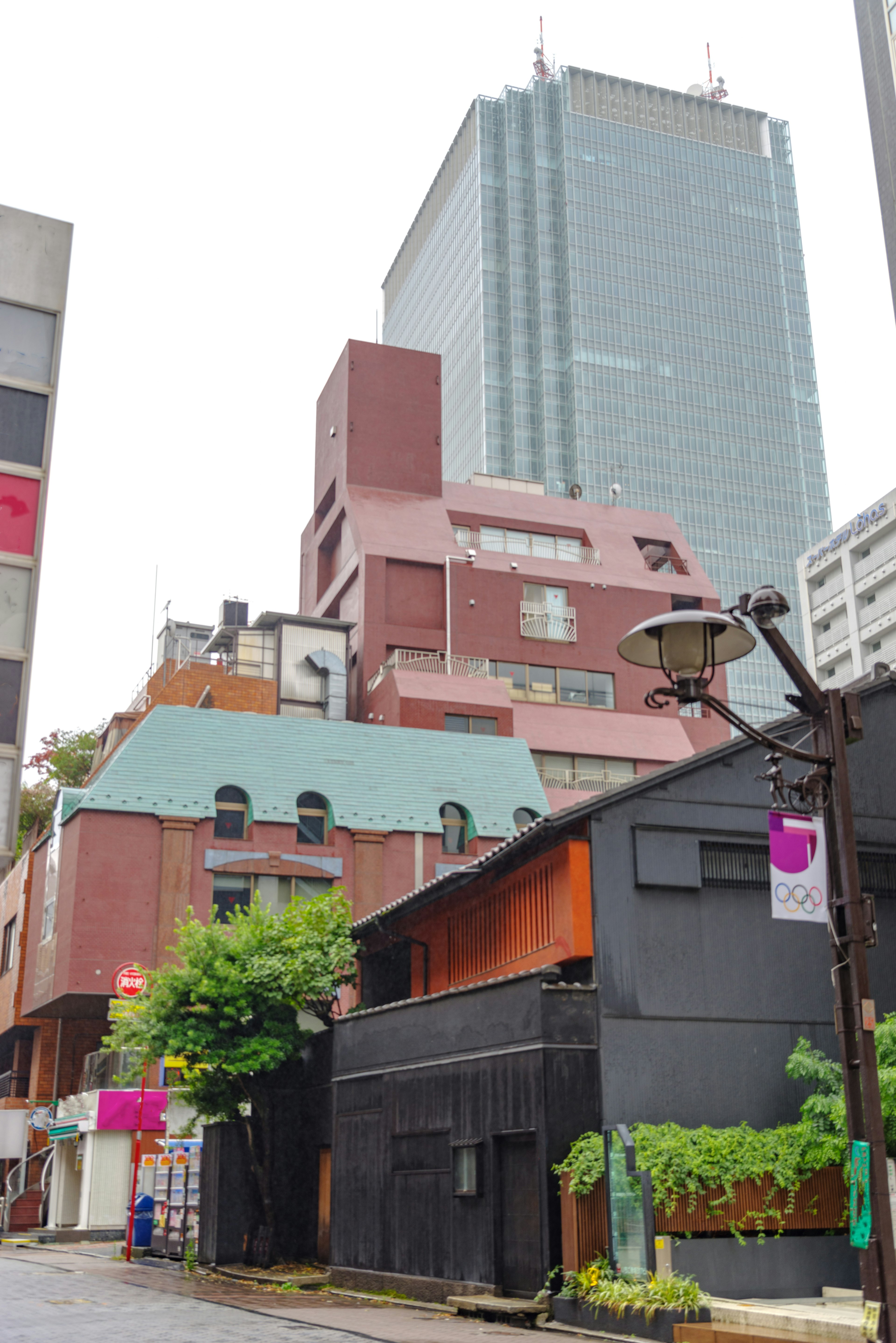 高層ビルと古い建物が混在する都市の風景 緑豊かな植物と街灯が特徴