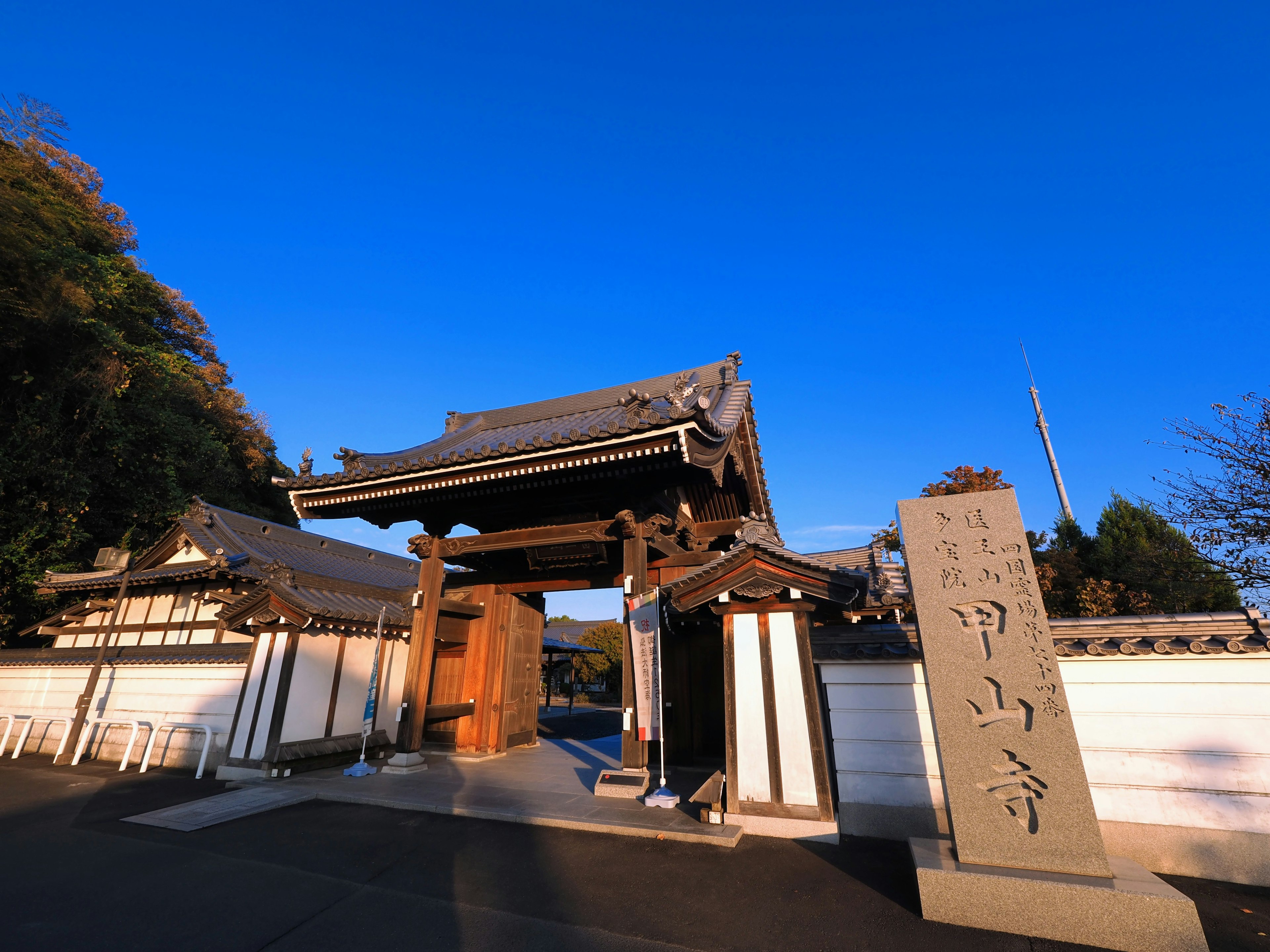 Puerta de templo japonés tradicional y monumento de piedra bajo un cielo azul