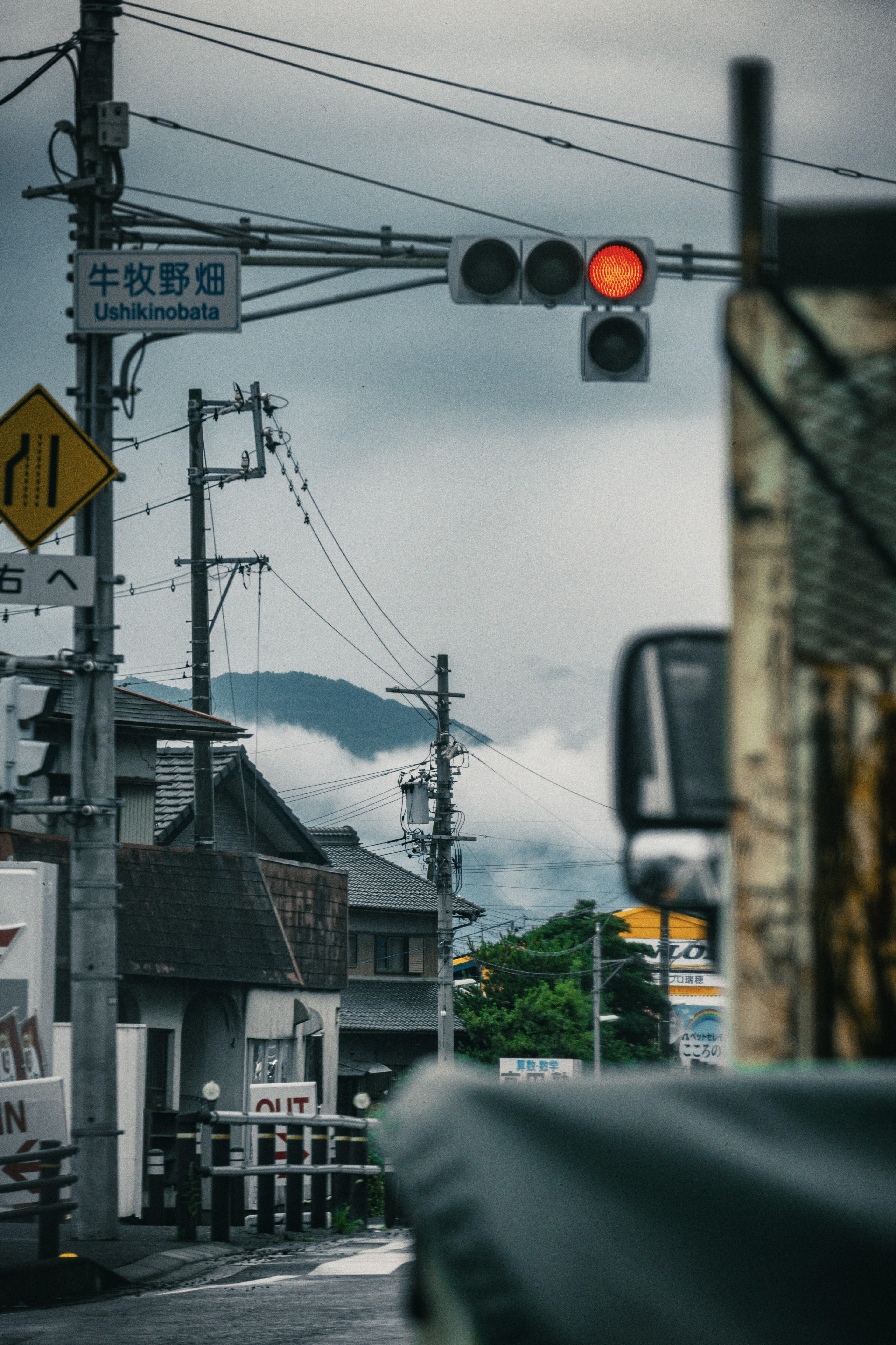 交通信号機が赤色で、山々が背景に見える静かな街並みの風景