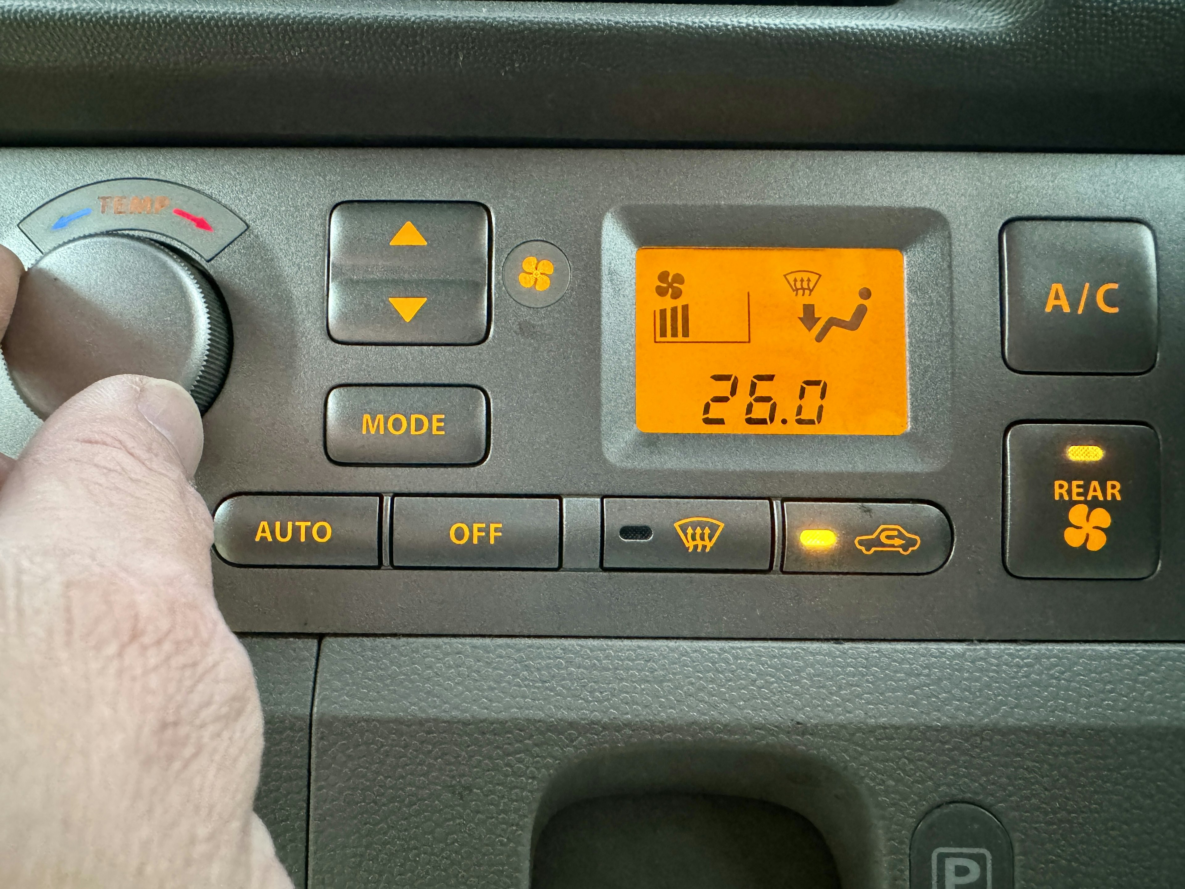 Mano ajustando el panel de aire acondicionado del coche Pantalla de temperatura a 26 grados Varios botones y controles