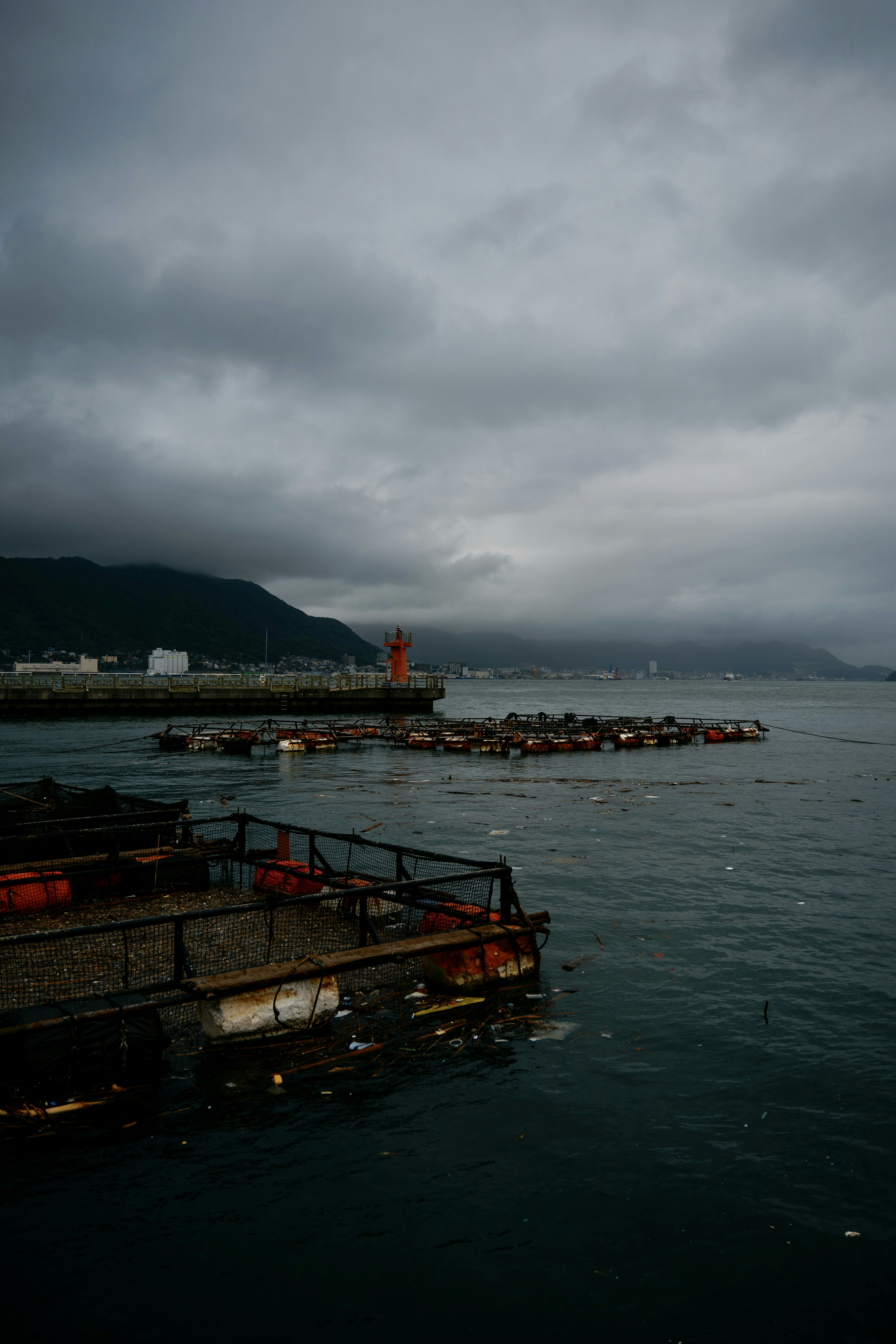 暗い雲に覆われた海と埠頭の景色赤い灯台と静かな水面