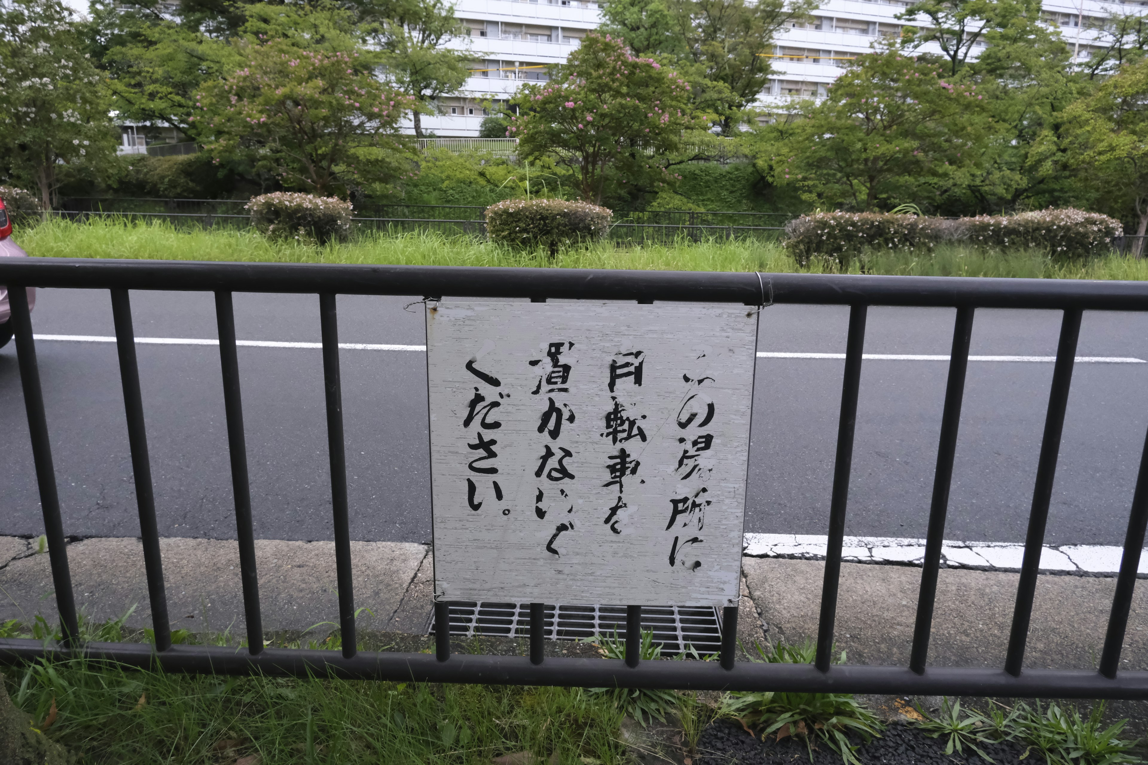 Cartel de advertencia en japonés pegado a una valla a lo largo de la carretera