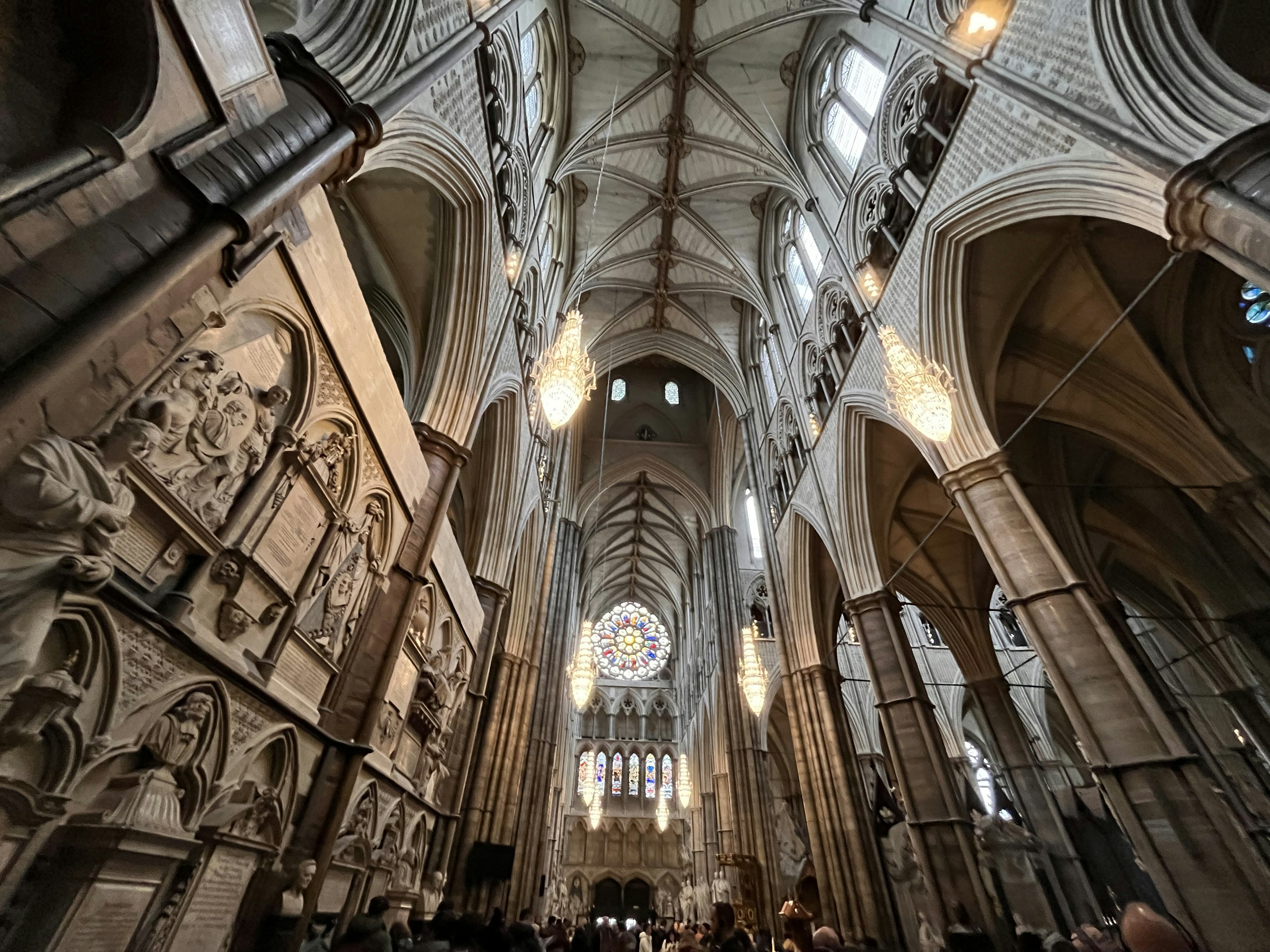 Interior of a grand cathedral featuring high ceilings and beautiful stained glass windows illuminated by chandeliers